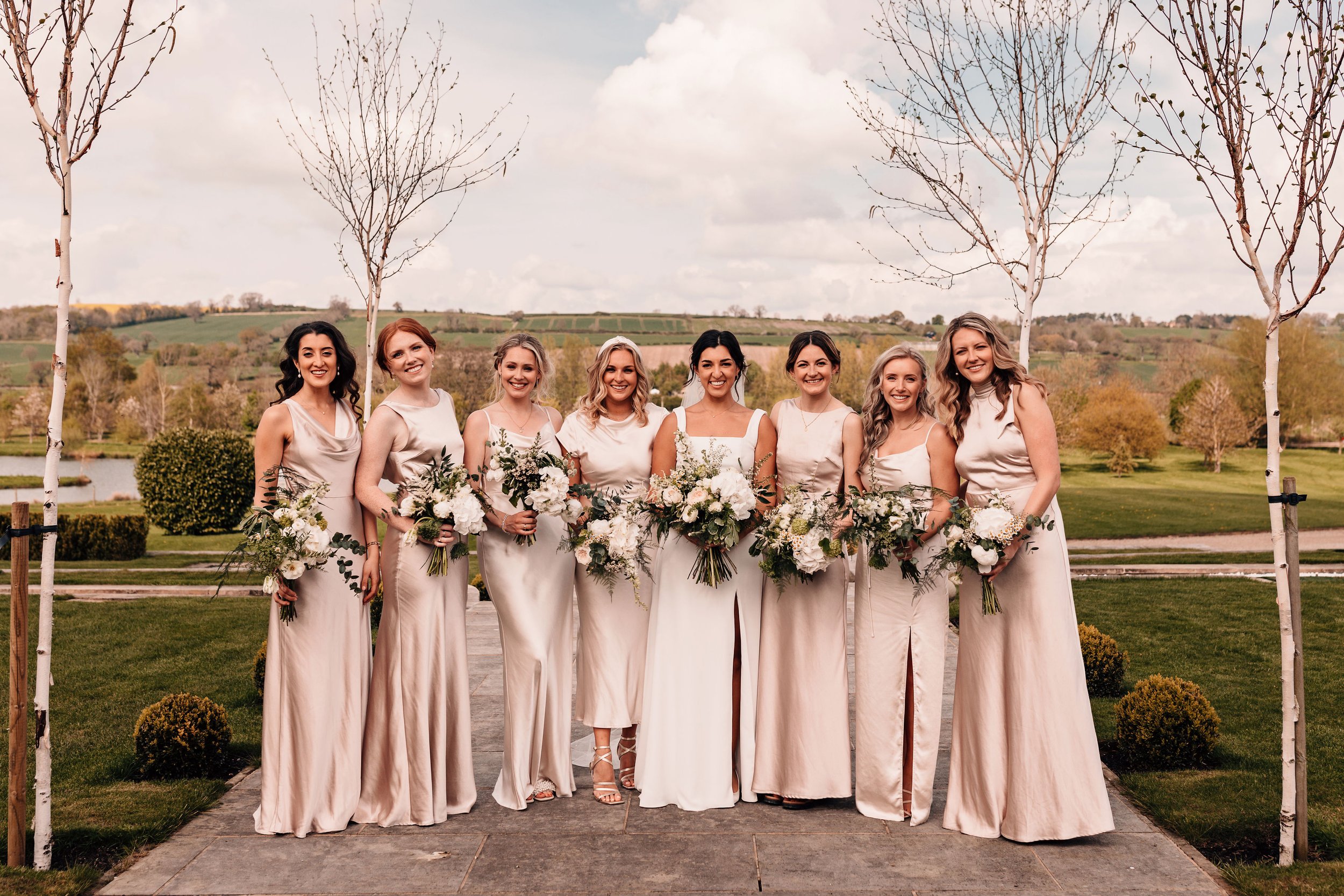 Bridesmaids in champagne tone dresses with seasonal florals