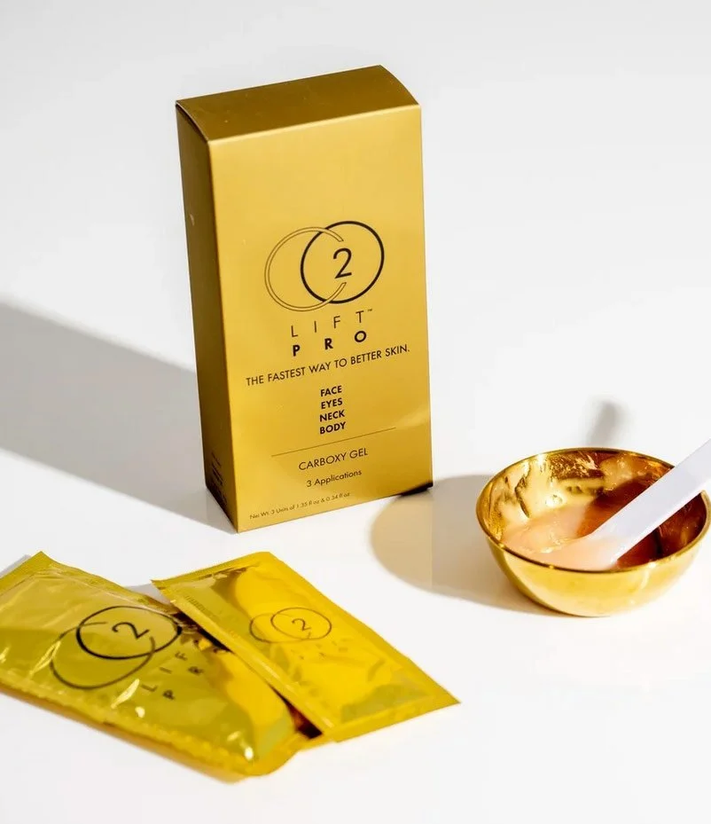 Gold box and packets of CO2LIFT PRO skincare product, with a gold bowl and spatula.
