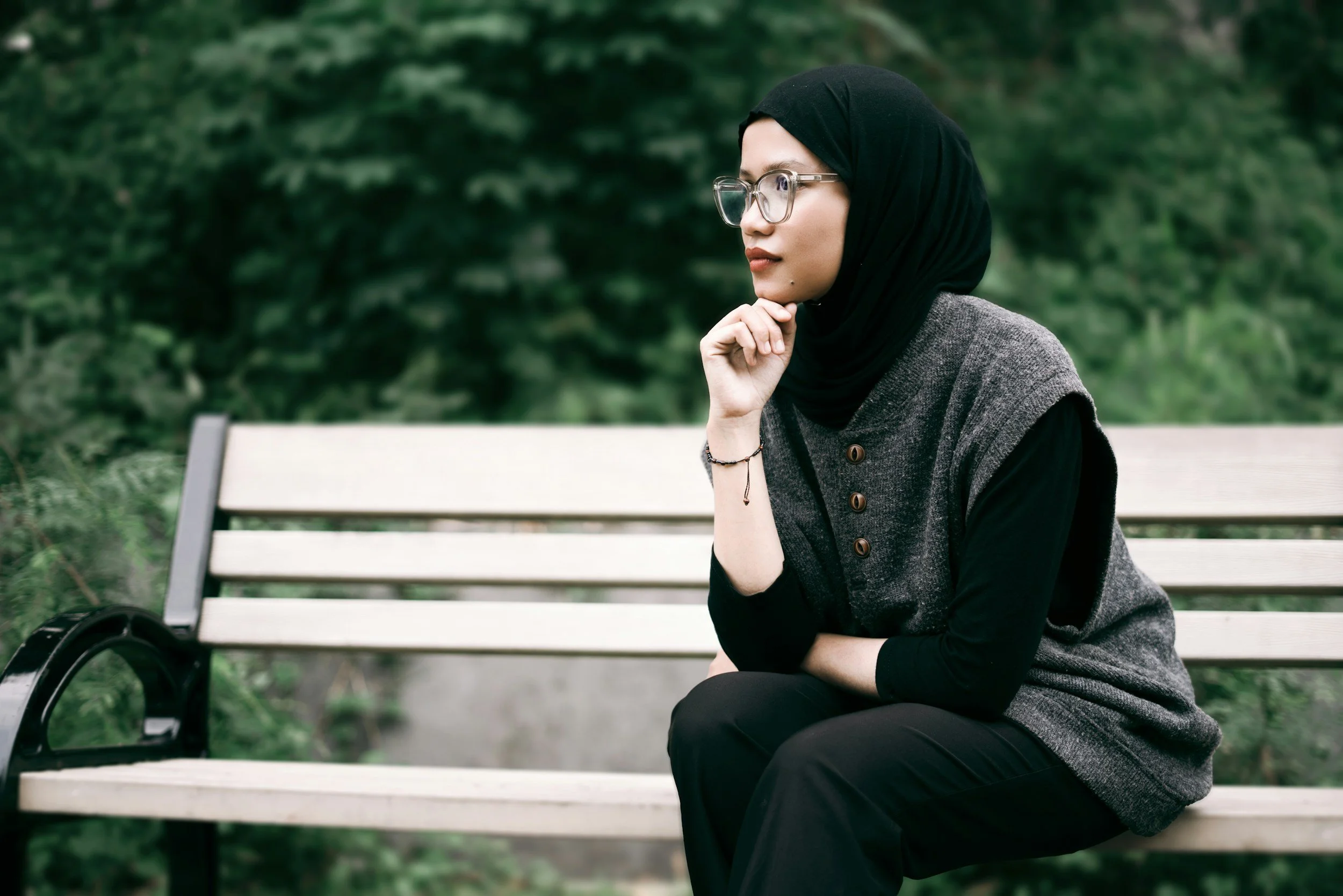 woman sitting on bench looking thoughtful | Learning about a new approach to chronic pain with curiosity and openness