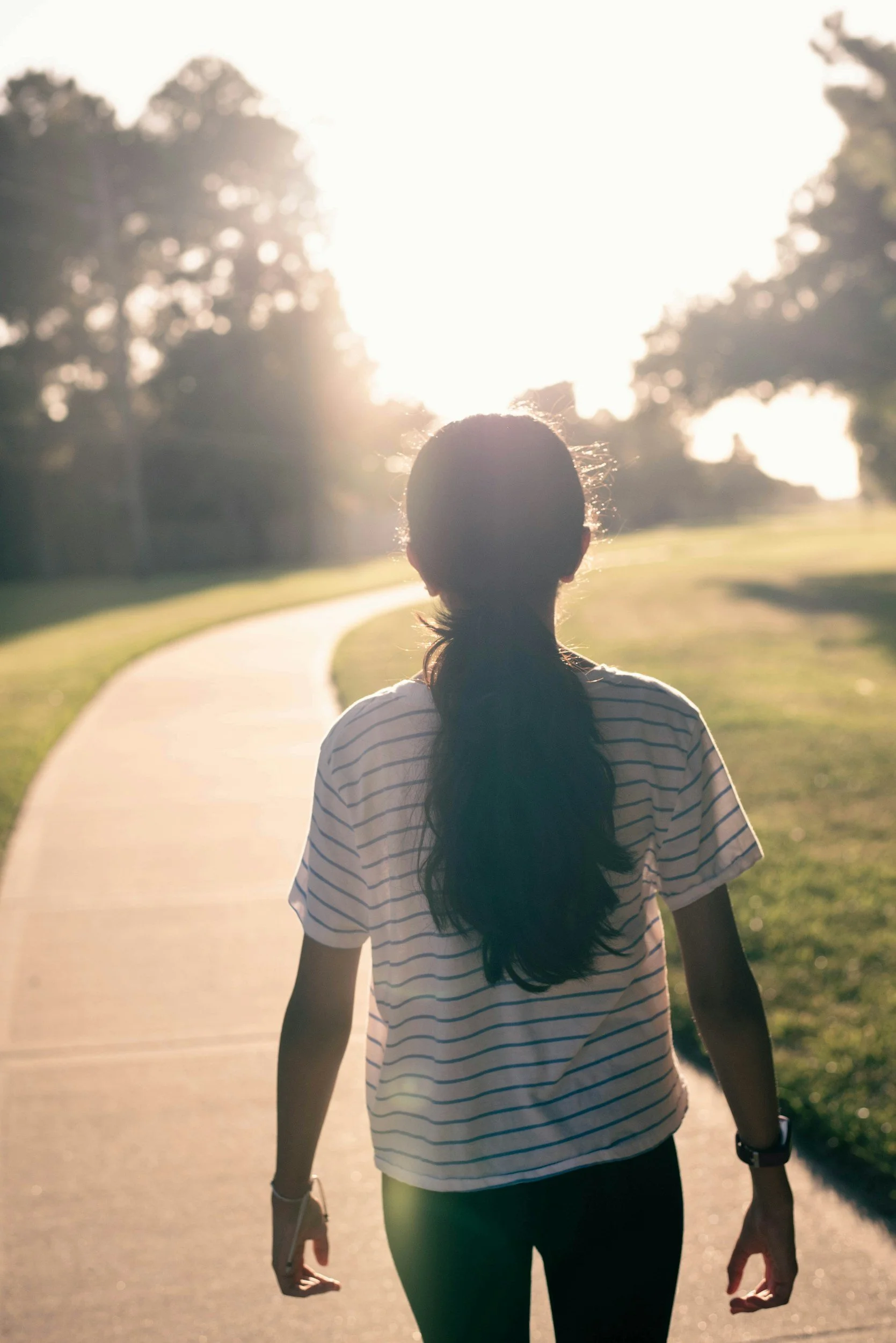 woman walking on path toward sunlight | Experiencing relief and movement through pain reprocessing therapy