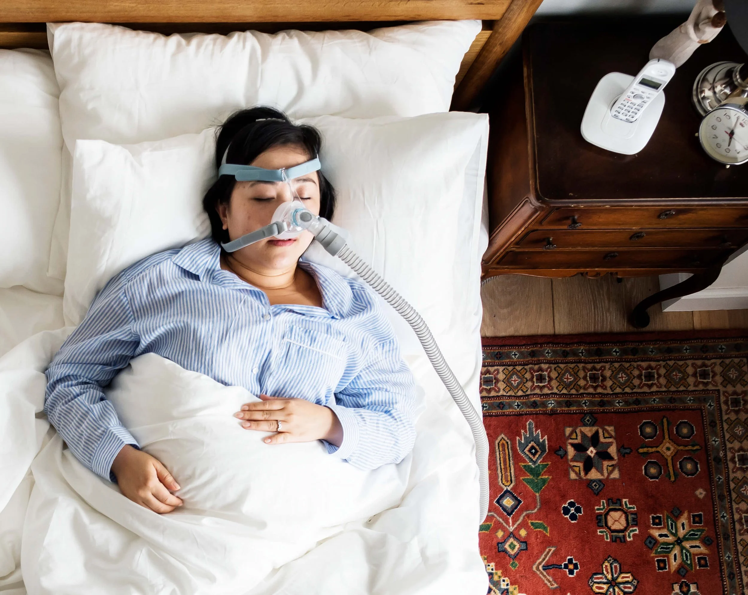 Adult sleeping in bed while using a CPAP machine to treat obstructive sleep apnea.
