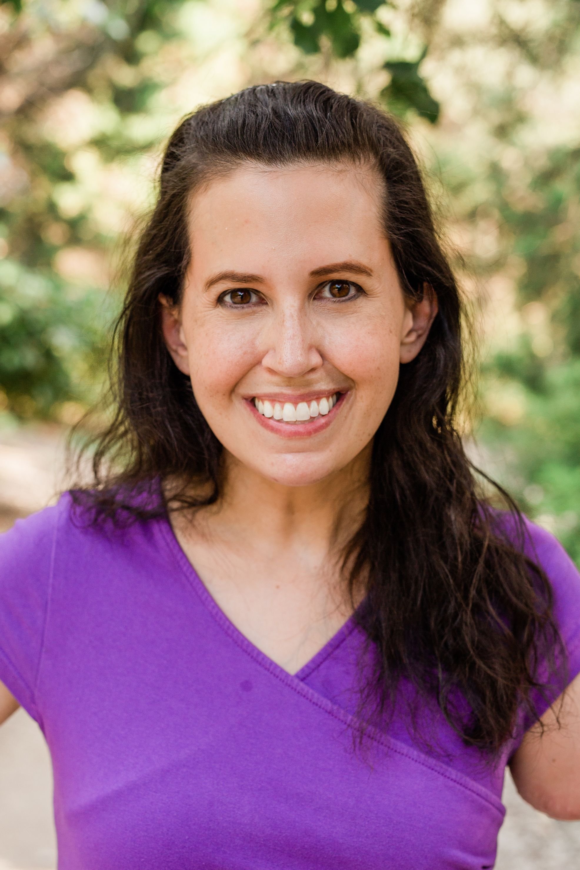 smiling woman with long brown hair in a purple top