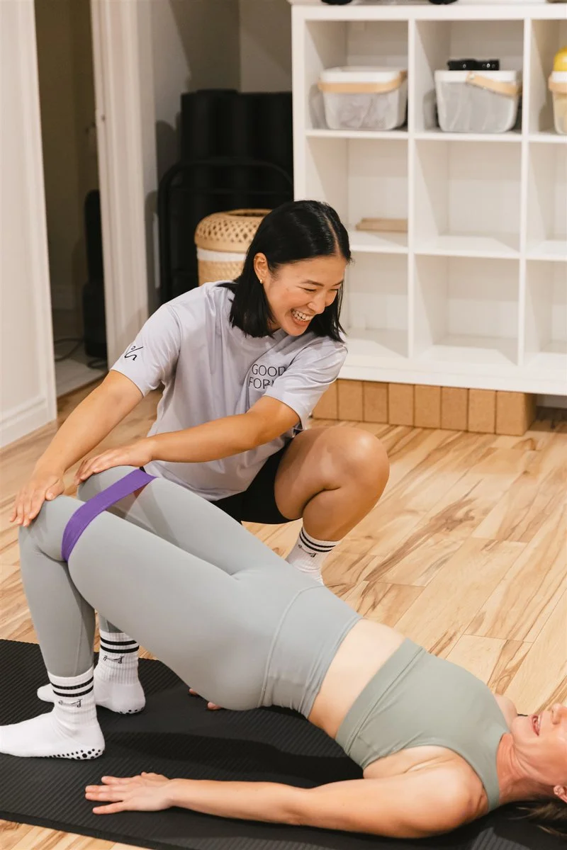 Mat Pilates instructor assisting client