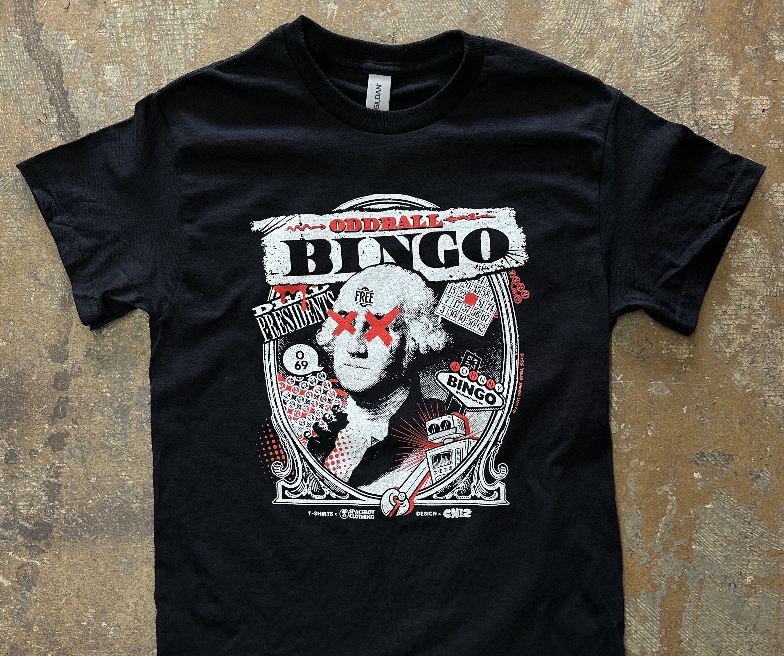 Black t-shirt with a graphic design featuring a stylized depiction of George Washington with red Xs over the eyes, bingo cards, and the words "Oddball Bingo."