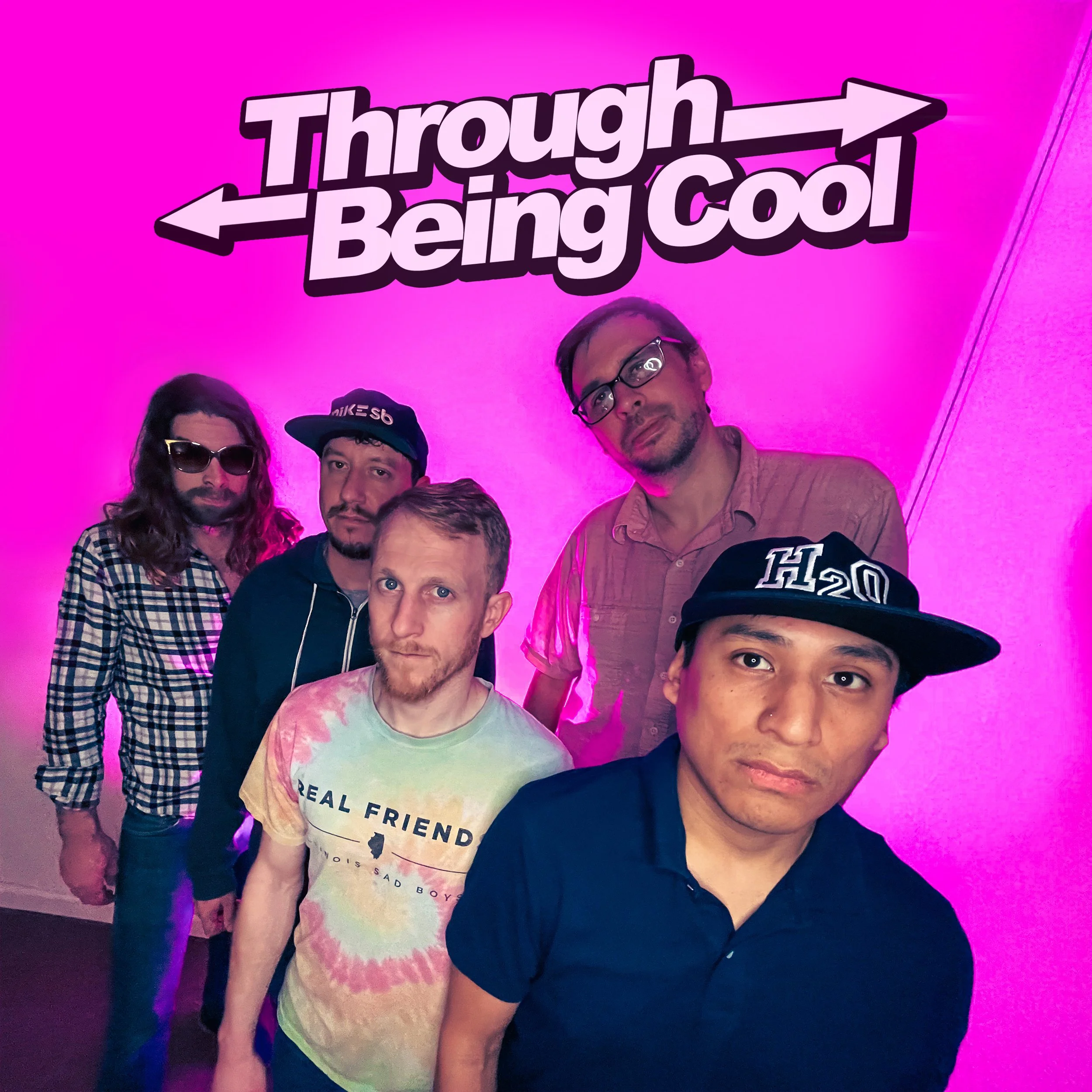 Five men standing together, posing in front of a purple-lit background with "Through Being Cool" text above them. The men are wearing casual clothes, some with hats and glasses.
