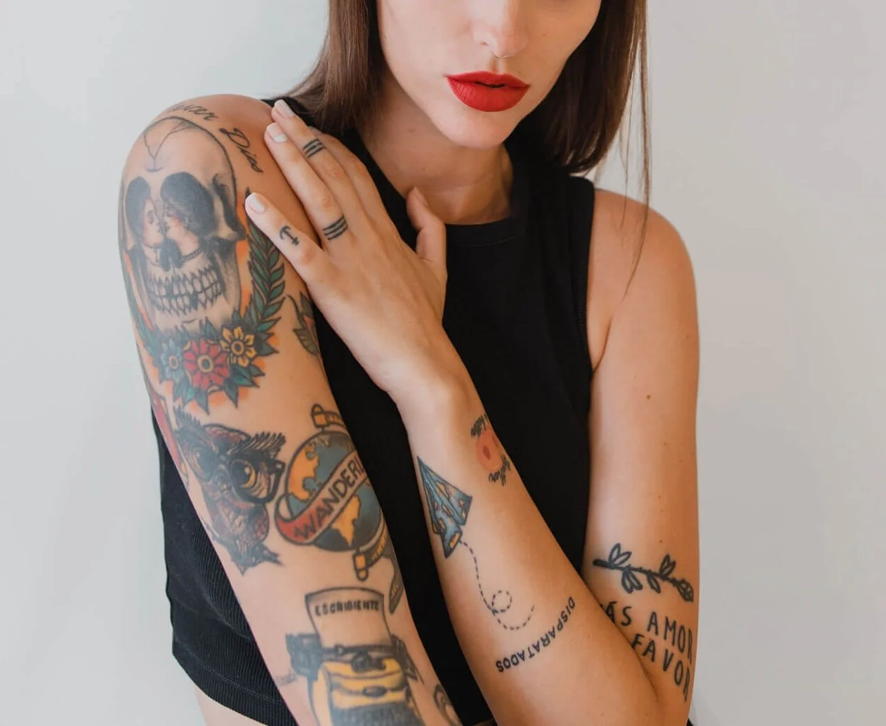 mujer artista con tatuajes de calaveras, aves, flores en los brazos y las manos