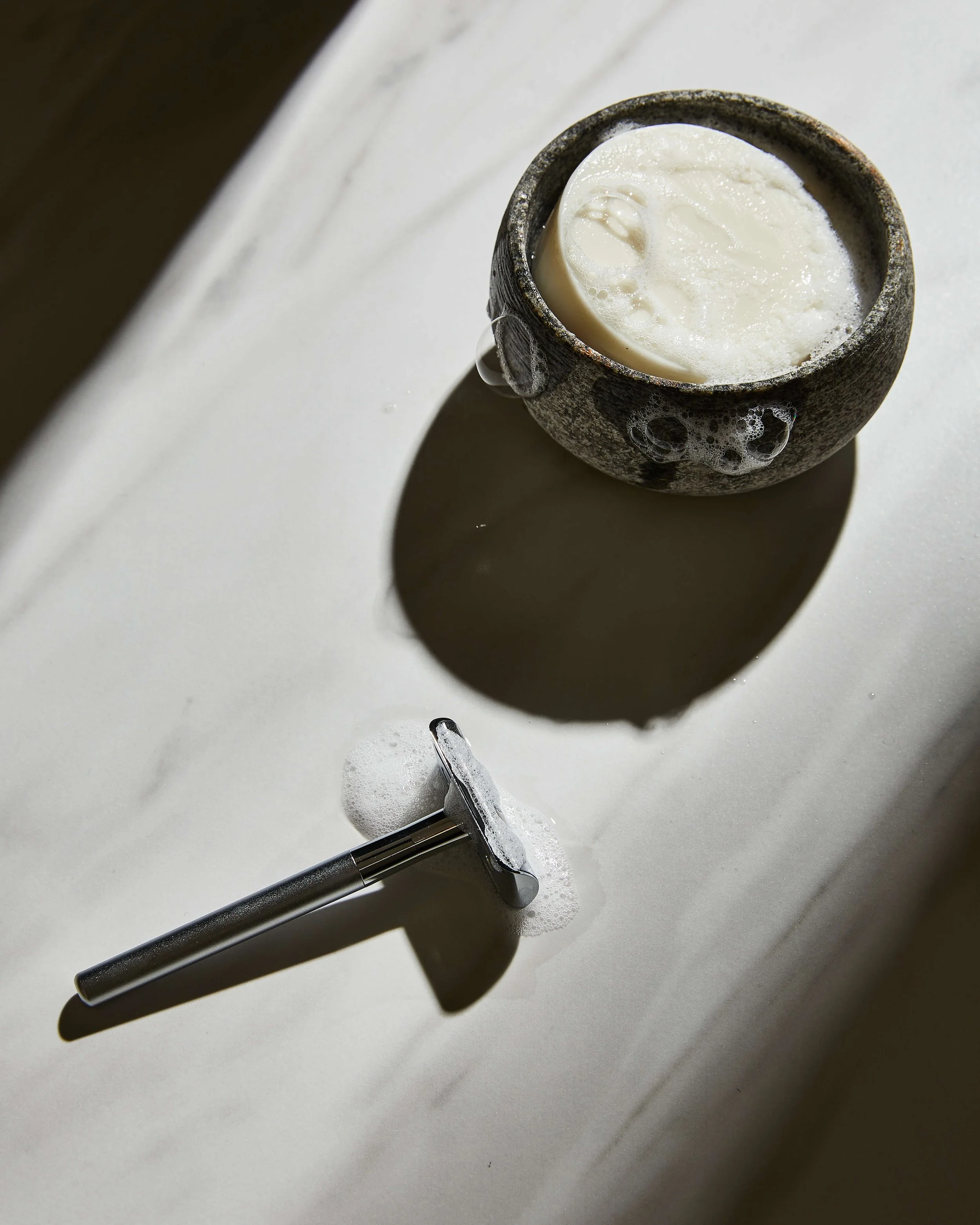 Rasierutensilien auf einer Marmoroberfläche.