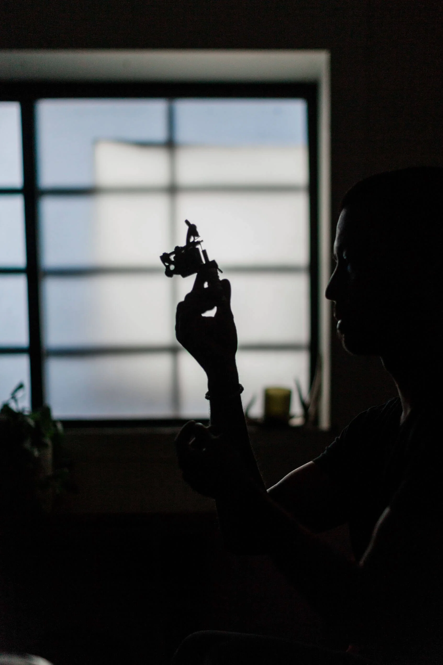 une main tenant un pistolet de tatouage dans un studio sombre