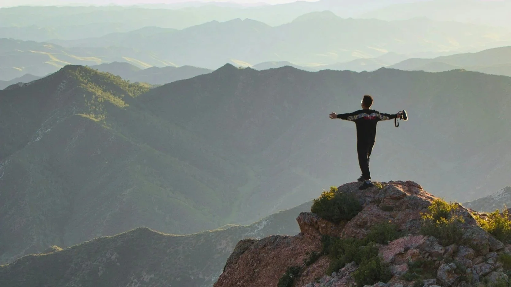 Small white chapel with green roof in desert landscape, mountains in background