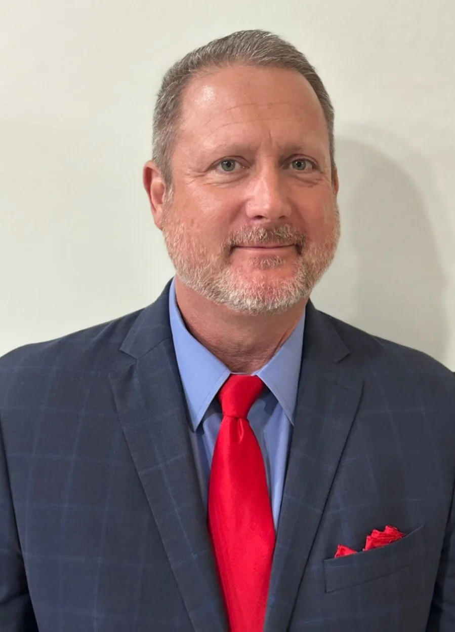 Image of Glenn Konowal in a suit, smiling at the camera