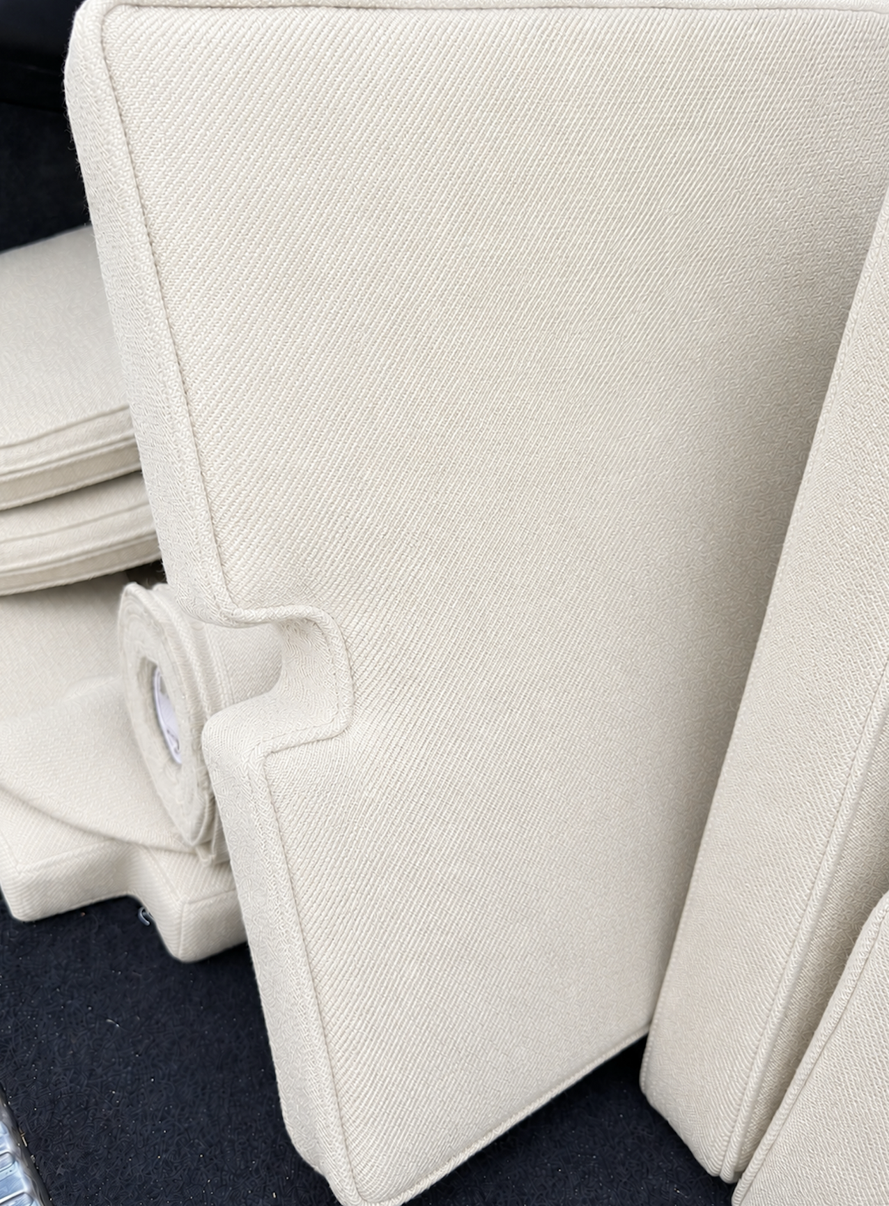 Witte gestoffeerde fauteuils en een ottoman op een zwarte vloer.