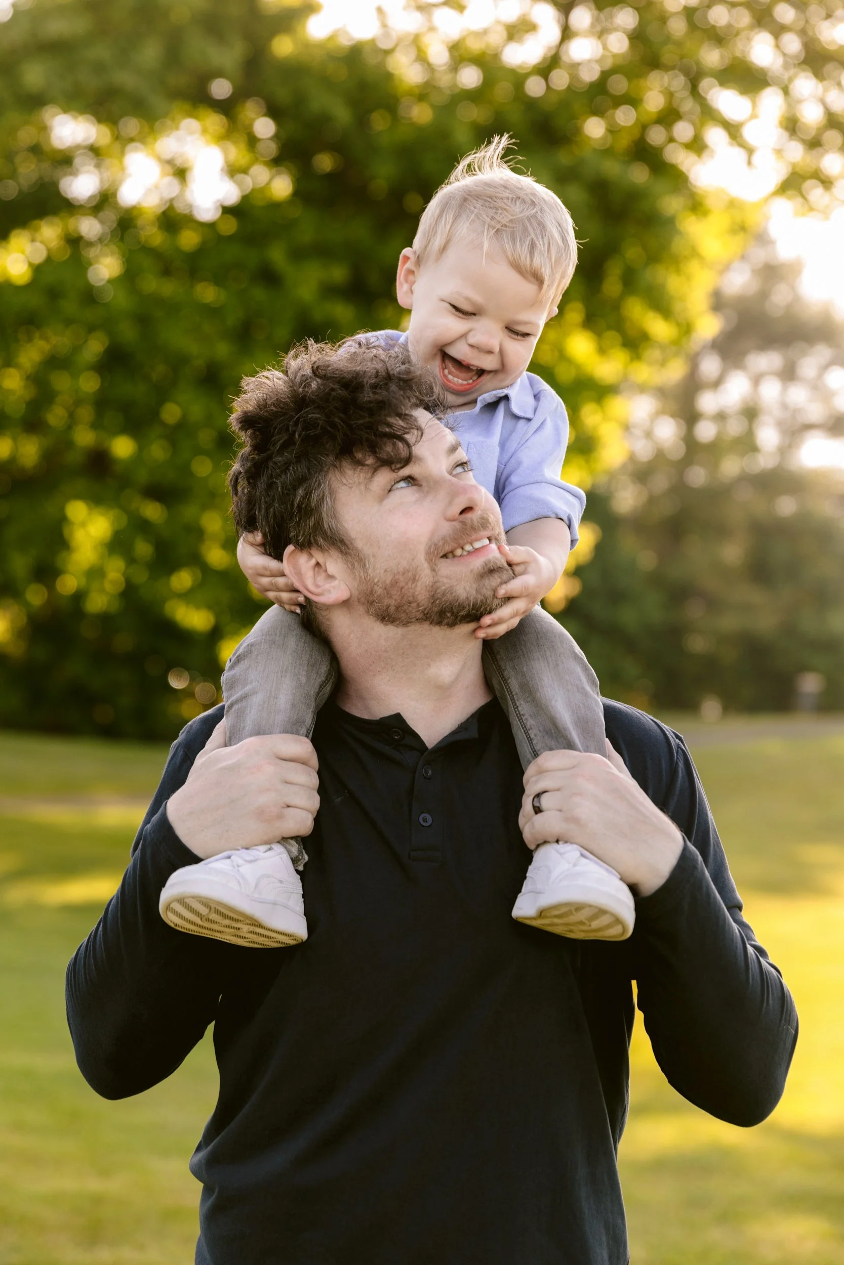  A father has his son up on his shoulders and is looking up at him 