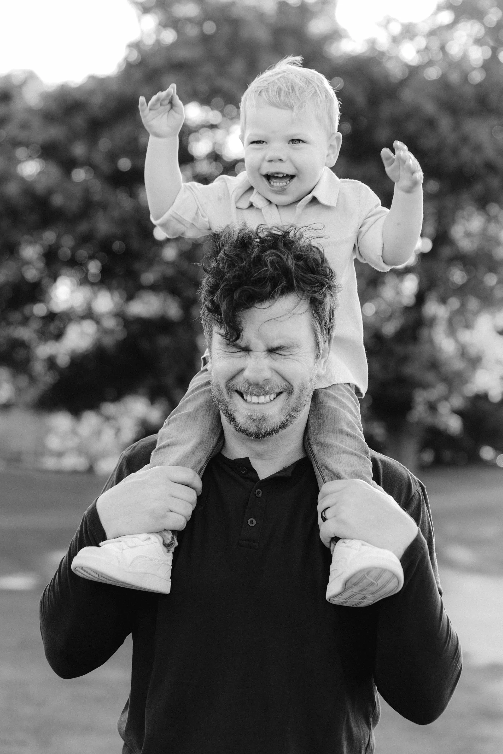  A black and white photo of a father with his young son on his shoulders being a ham 
