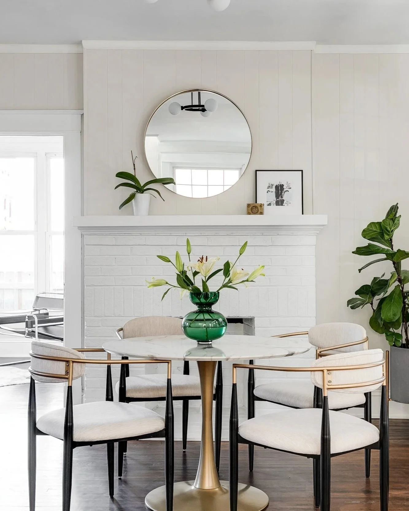Custom dining room design from Designs Delivered featuring a styled round marble table, white brick fireplace, and modern seating, showcasing the personalized results available in the design customization services