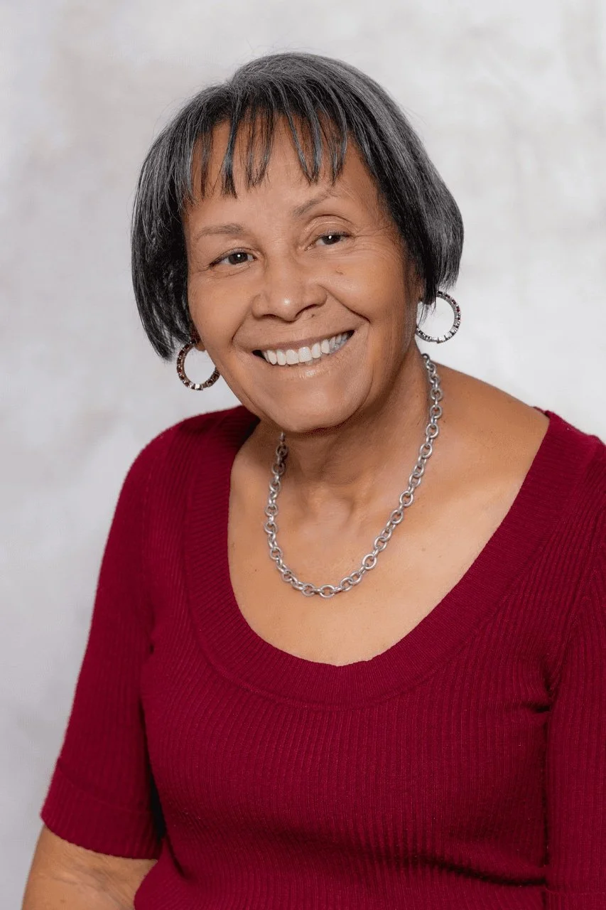 Smiling woman wearing a red sweater and silver chain necklace.