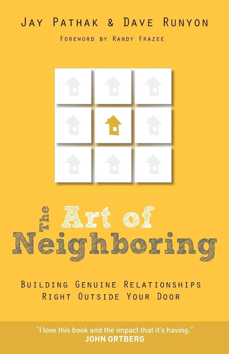 Book cover titled "The Art of Neighboring" by Jay Pathak & Dave Runyon with foreword by Randy Frazee. The cover has a yellow background with a grid of nine white squares, the middle square highlighted in yellow featuring a house icon. The subtitle reads "Building Genuine Relationships Right Outside Your Door." A quote at the bottom says, "I love this book and the impact that it’s having." - John Ortberg.