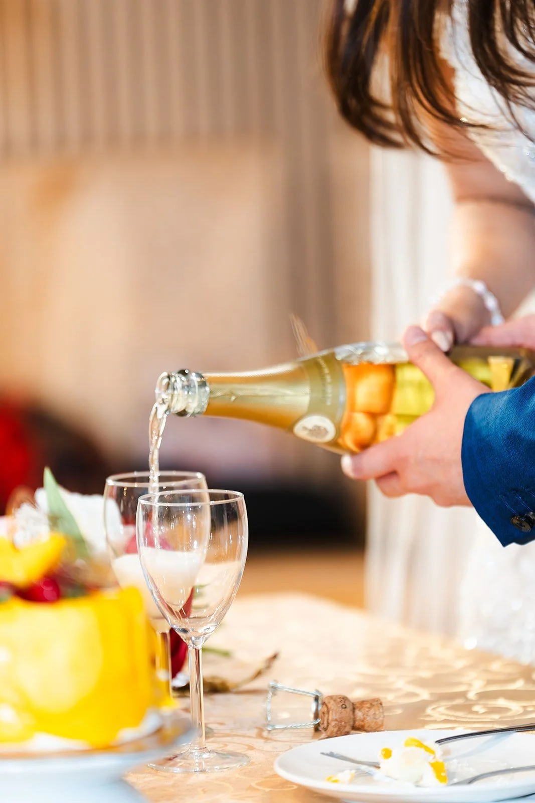 Person pouring champagne into glasses at a celebration or party.