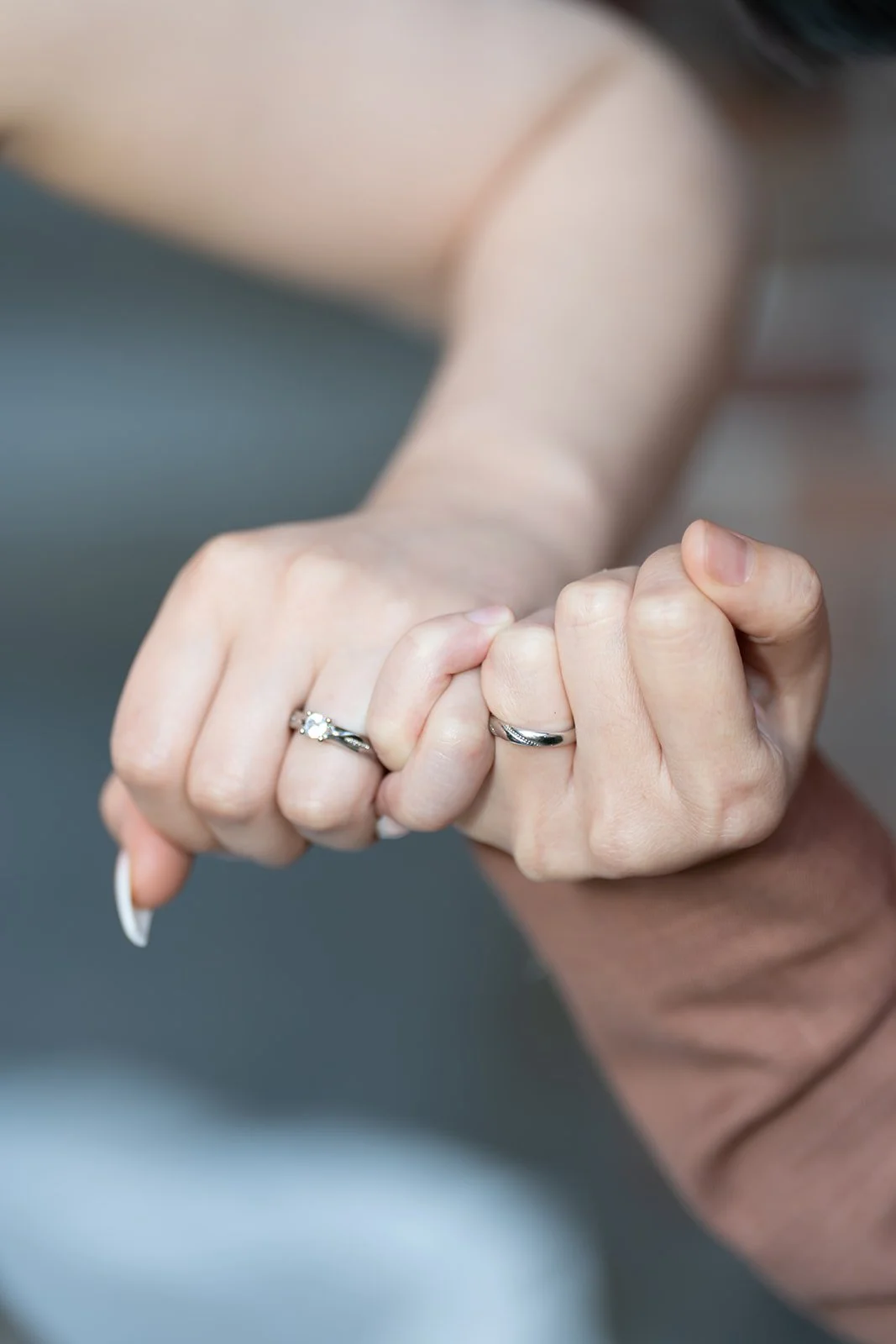 Close-up of two hands with wedding rings clasping each other.