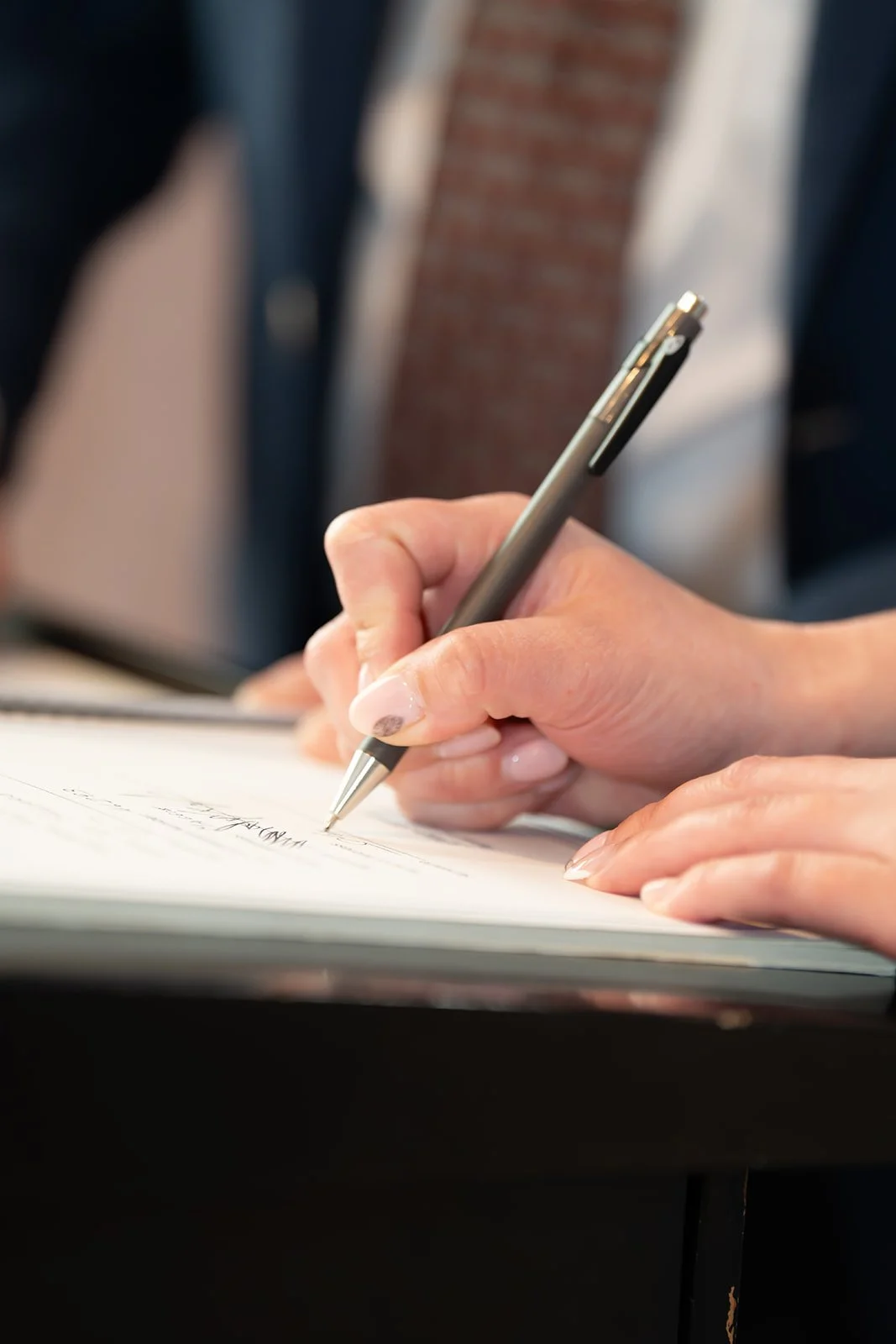 A person holding a pen and writing in a notebook.