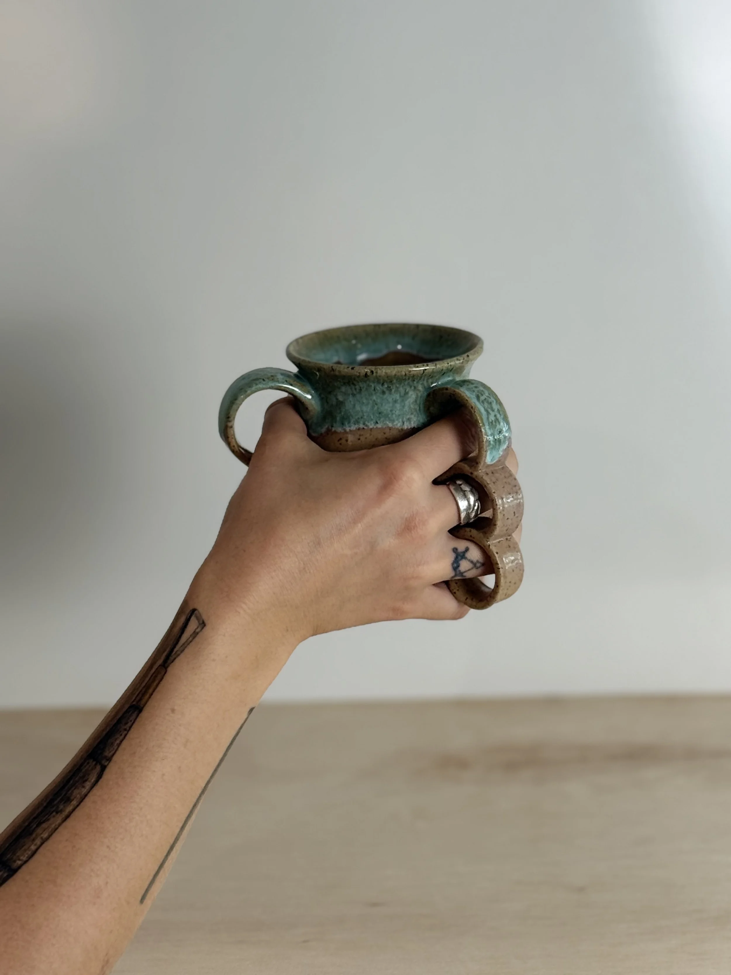 Hand holding a mug with many handles