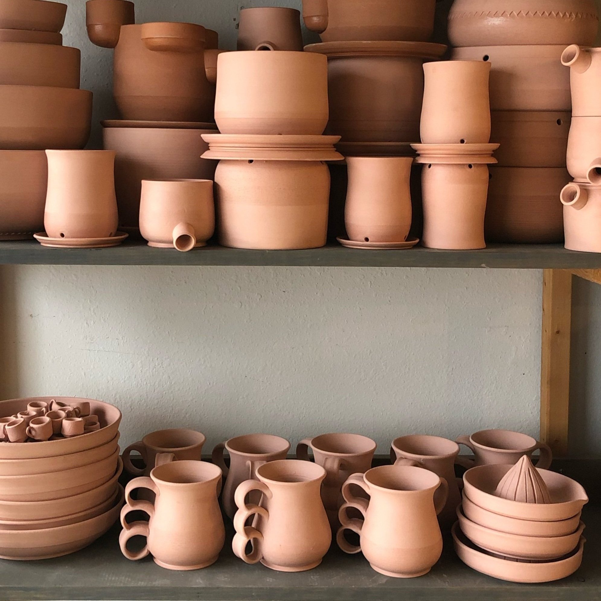 Stacks of bisqued pottery on shelves
