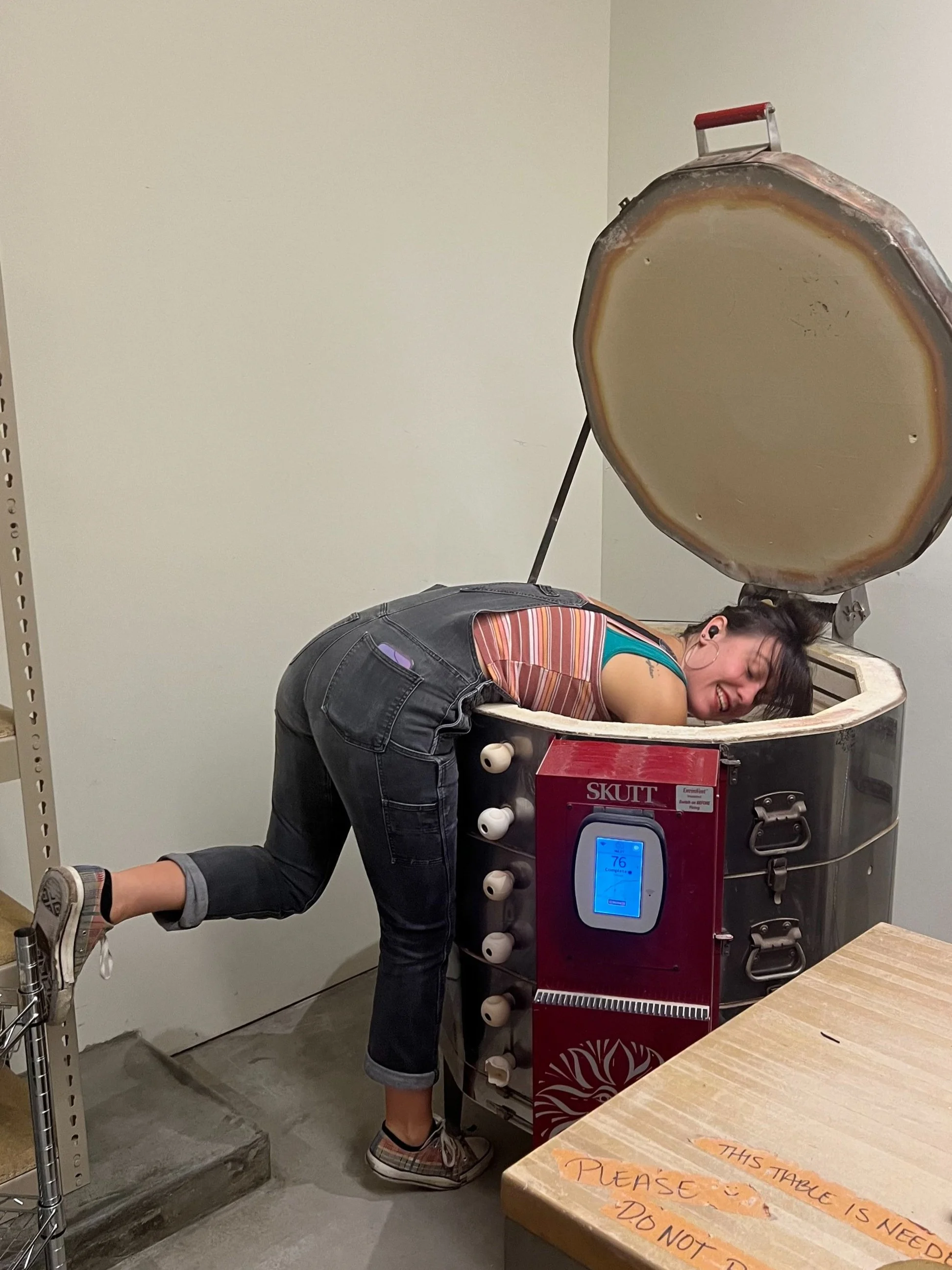 Woman bent over loading a Skutt kiln