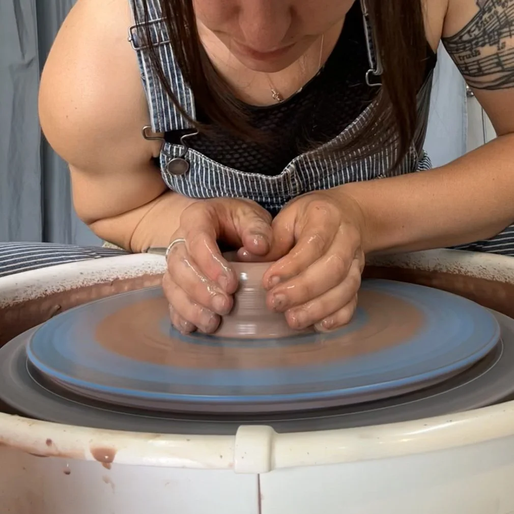 Woman throwing clay on a pottery wheel