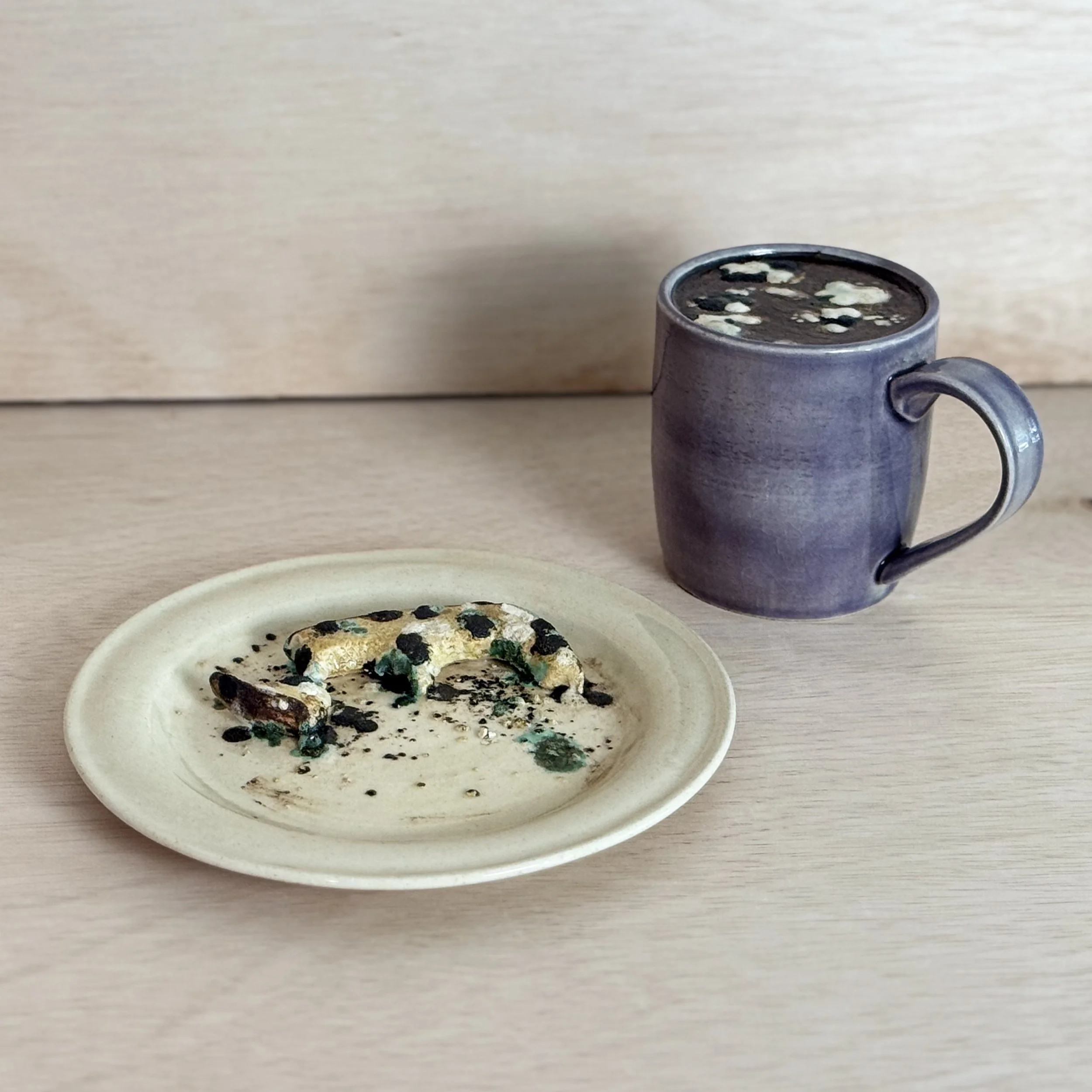ceramic sculpture of mug and plate that have moldy food