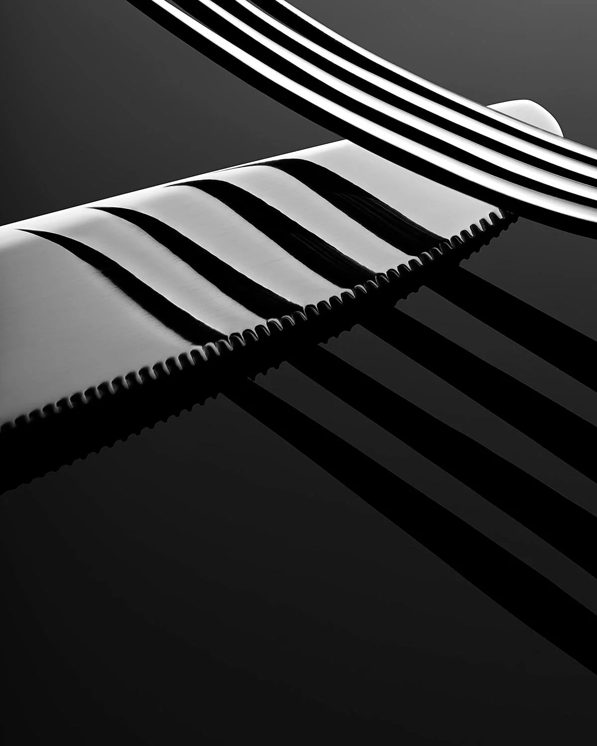 Close-up of a piano keyboard with black and white keys, casting shadows on a dark surface, in black and white.