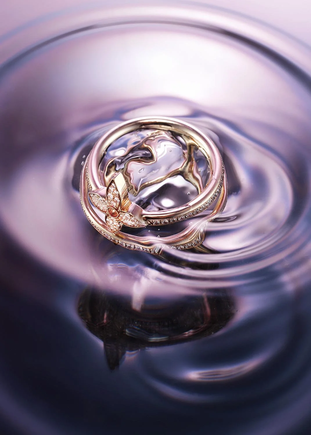 A close-up of a jewelry ring with a butterfly design, floating on a reflective water surface with ripples