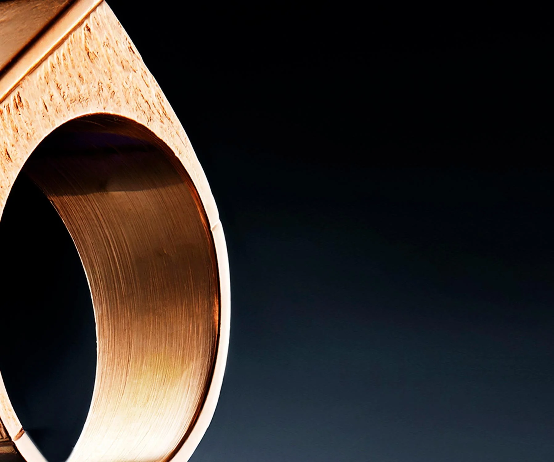 Close-up of a wooden and metal cylinder against a dark background.