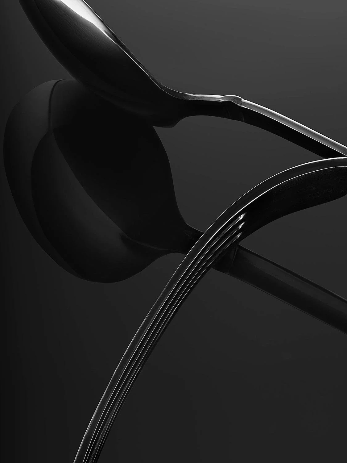 Close-up of a modern black chair with metal legs against a dark background.