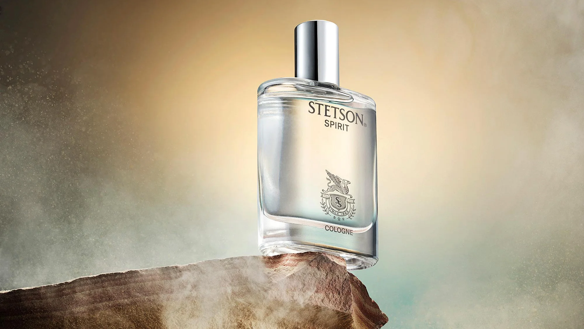A bottle of Stetson Spirit cologne is displayed on a rock with a blurred, gradient background.