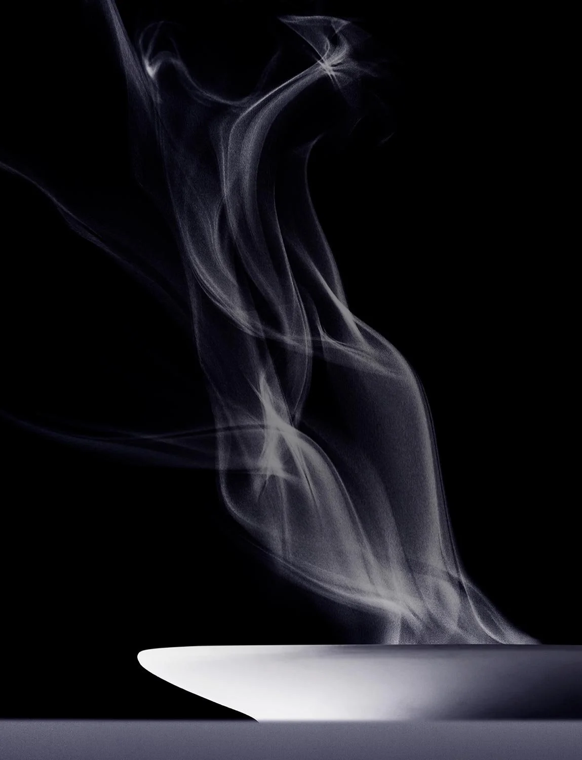 White bowl with wisps of smoke rising against a black background.