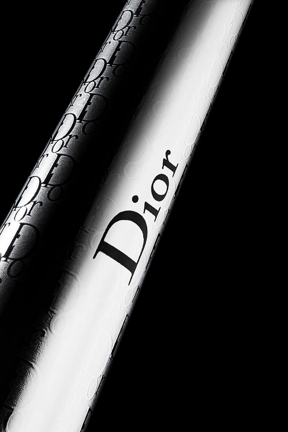 Close-up of a silver aerosol can with the word 'Dior' on it, on a black background, with water droplets on the can.