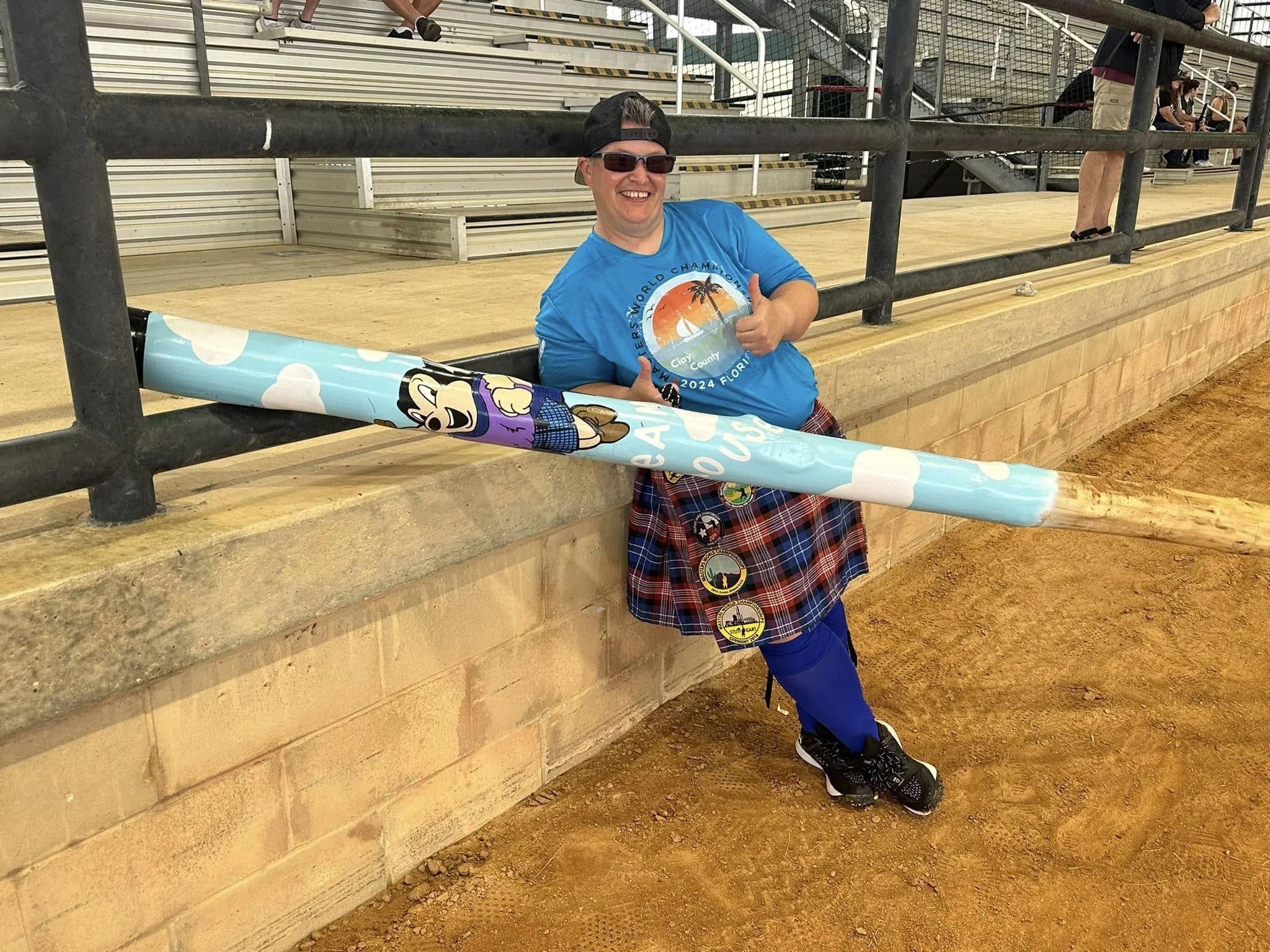 Courtney McGuire, holding a caber painted with Mighty Mouse