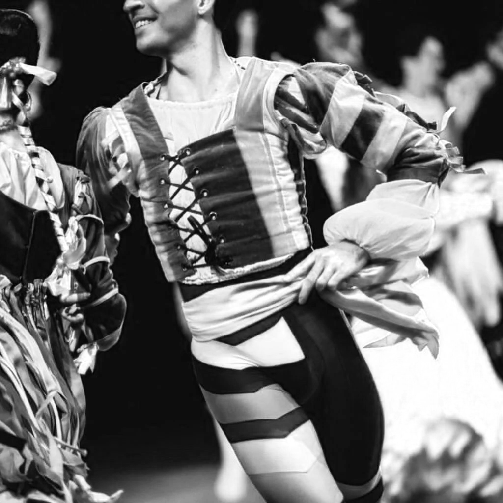A woman in traditional folk costume smiling and holding a ribbon, celebrating at a festival.