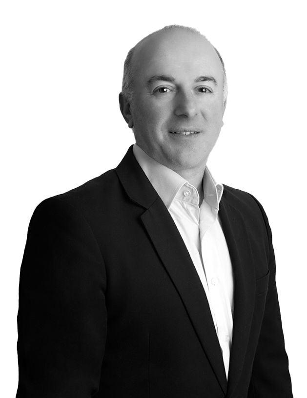 Black and white portrait of a middle-aged man in a suit and white dress shirt, smiling slightly, with a plain background.