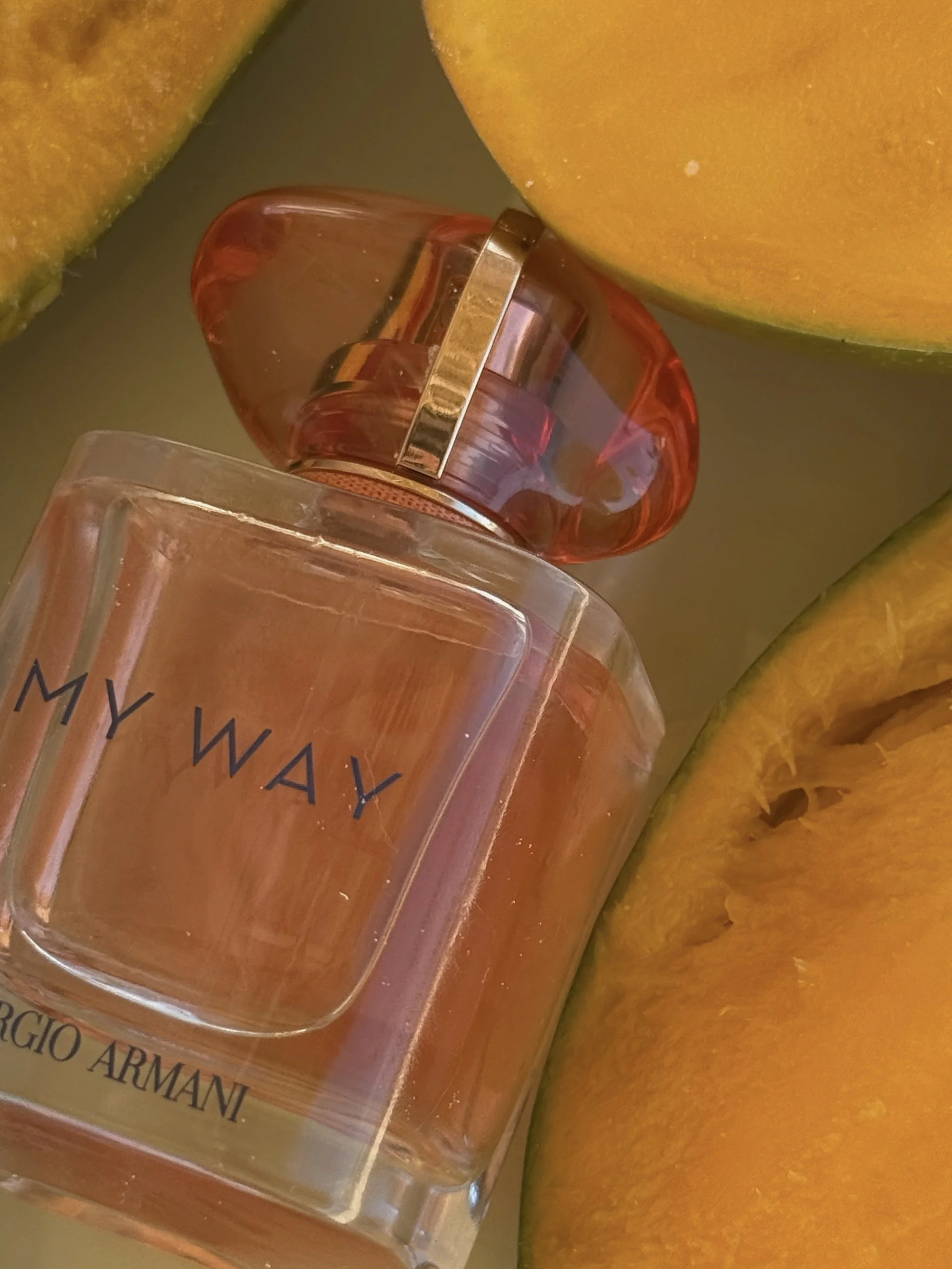 Frasco de perfume de Giorgio Armani llamado 'My Way' rodeado de rebanadas de mango.
