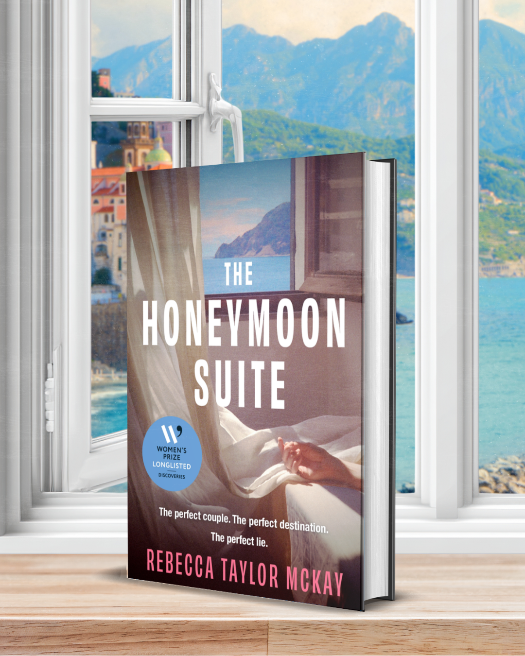 the image shows a book in front of an open window with a view of a Mediterranean coastline beyond