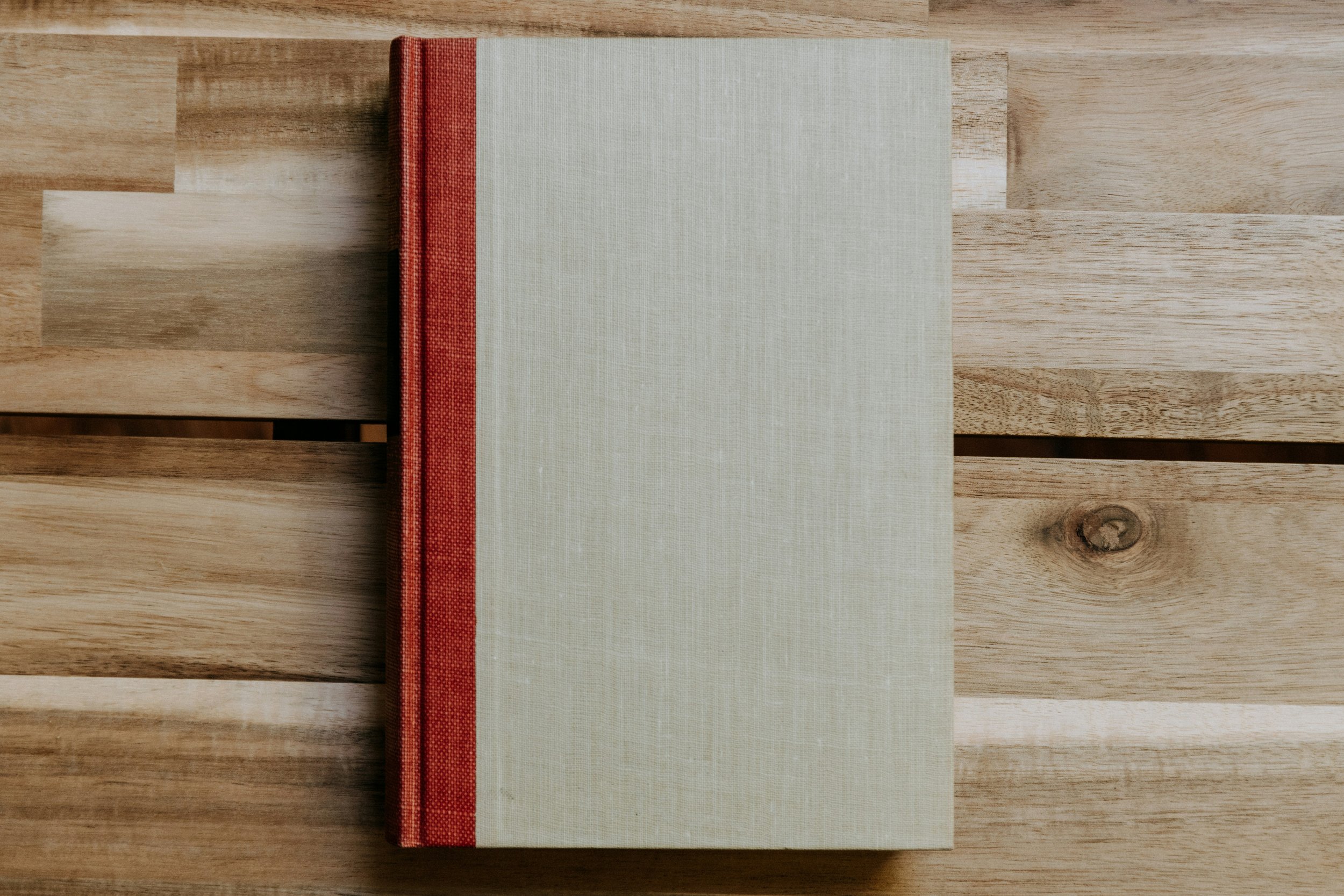 image shows a hardback book on a wooden tabletop, the book cover is blank
