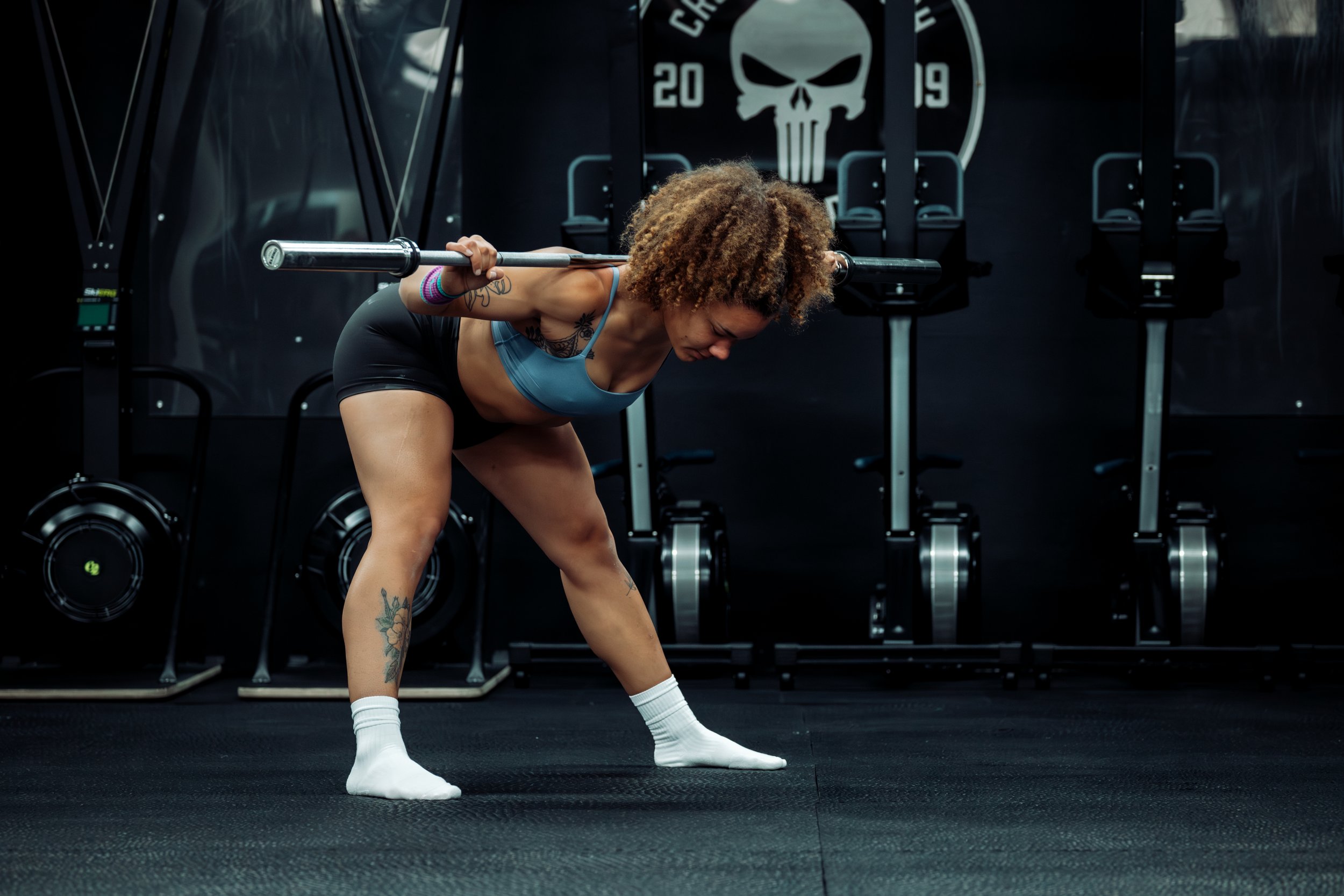 a coach demonstrates a barbell goodmorning