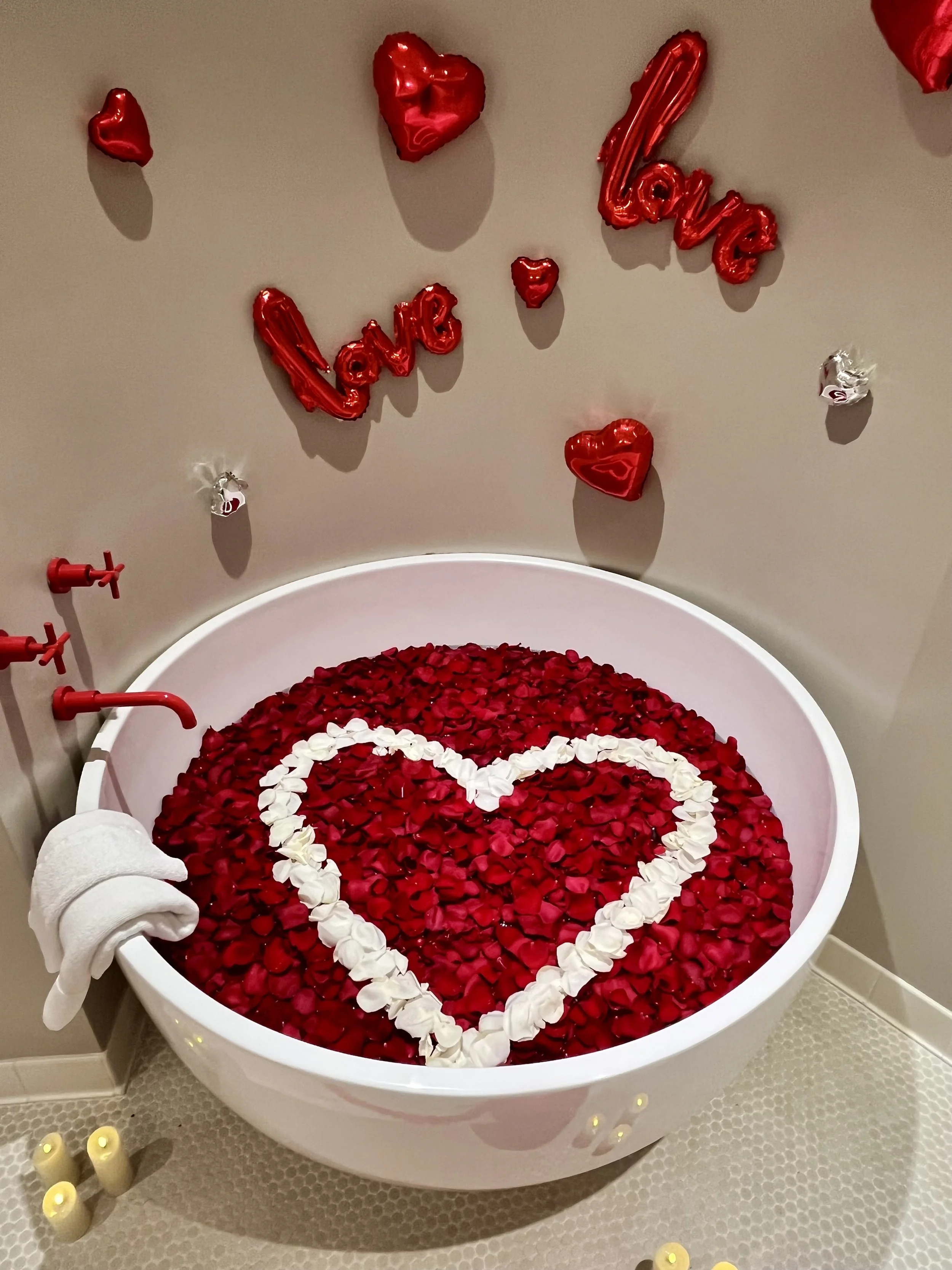 Romantic soaking tub filled with real red and white rose petals arranged in a heart shape, creating a luxurious romantic experience for hotel room décor in Dallas-Fort Worth.