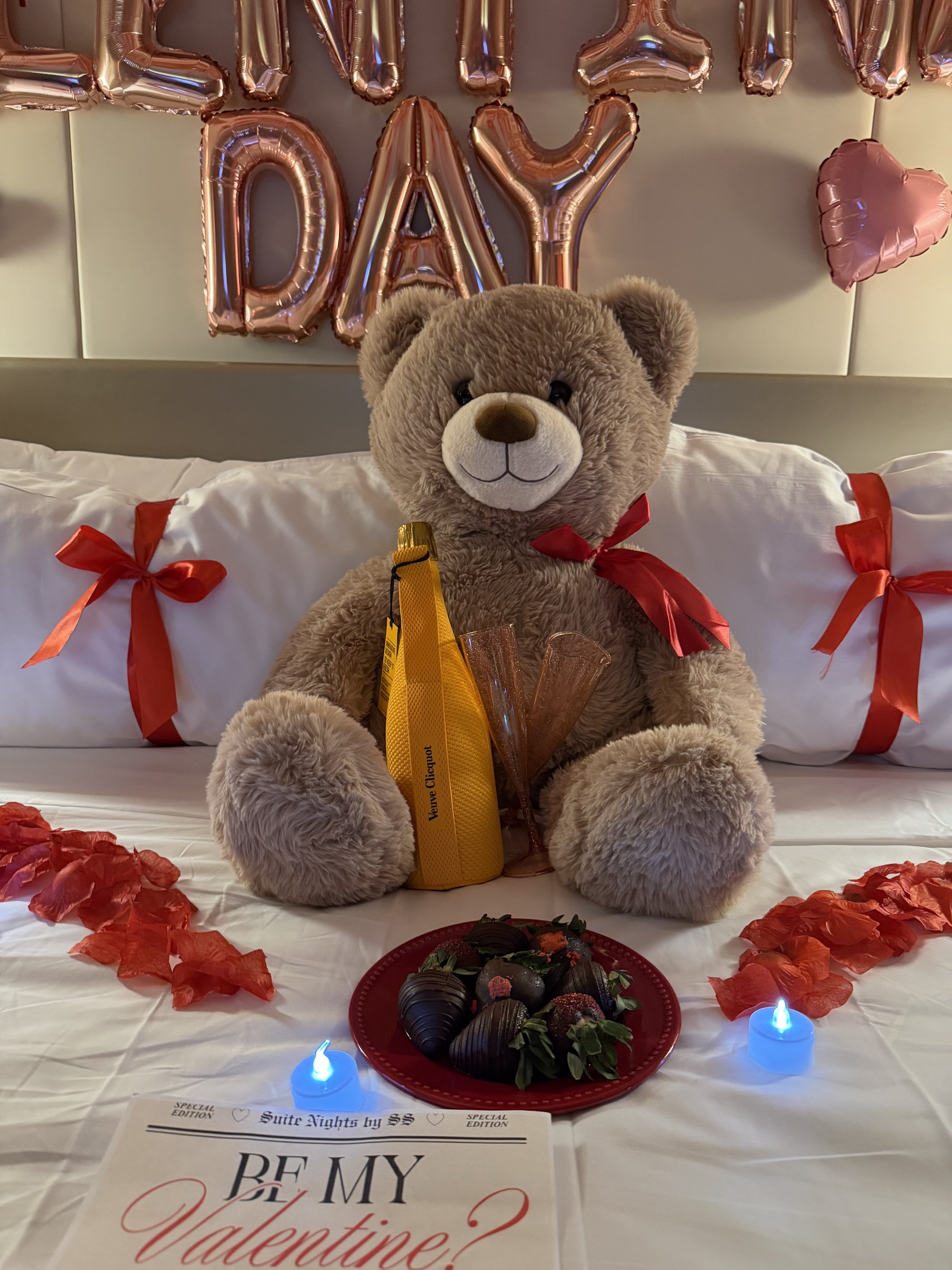 Giant brown teddy bear holding a Veuve Clicquot champagne bottle
