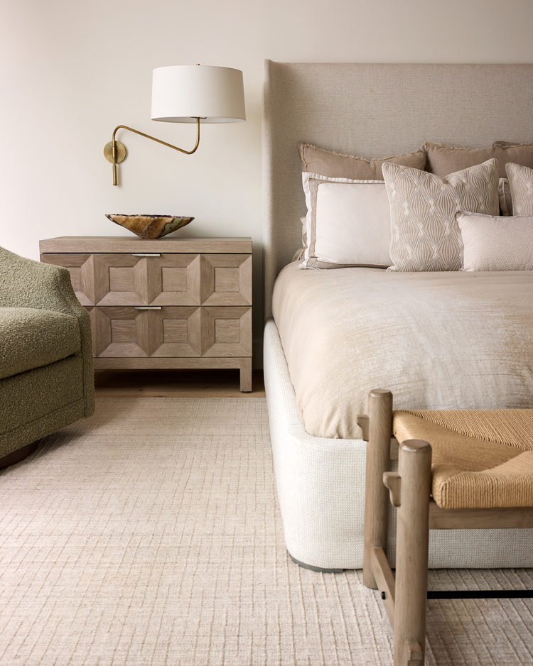Coastal luxury bedroom design with neutral bedding, textured furnishings, wood accents, and soft layered lighting.