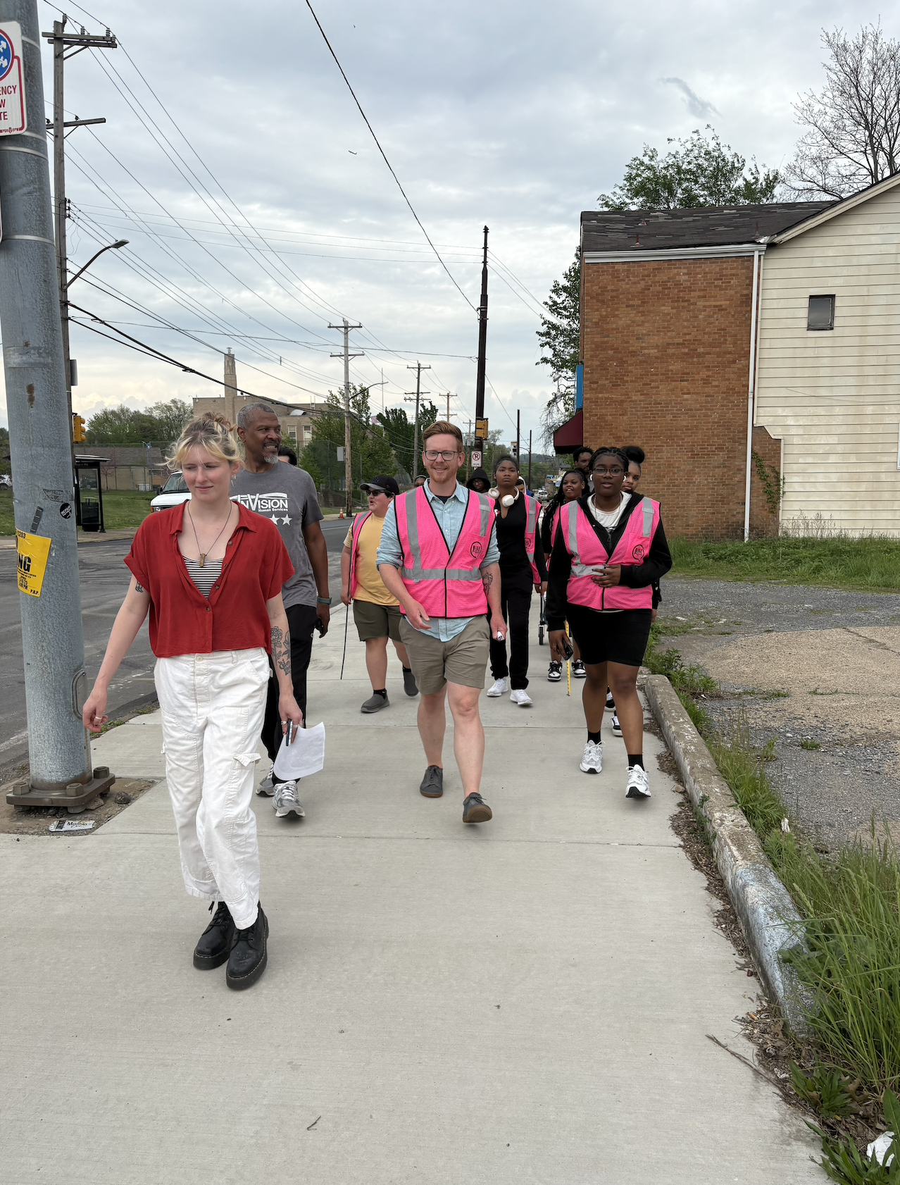 Volunteers walk down Hamilton Ave wearing pink safety vests