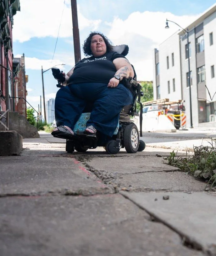 Alisa Grishman, disability advocate and wheelchair user, navigates a broken sidewalk