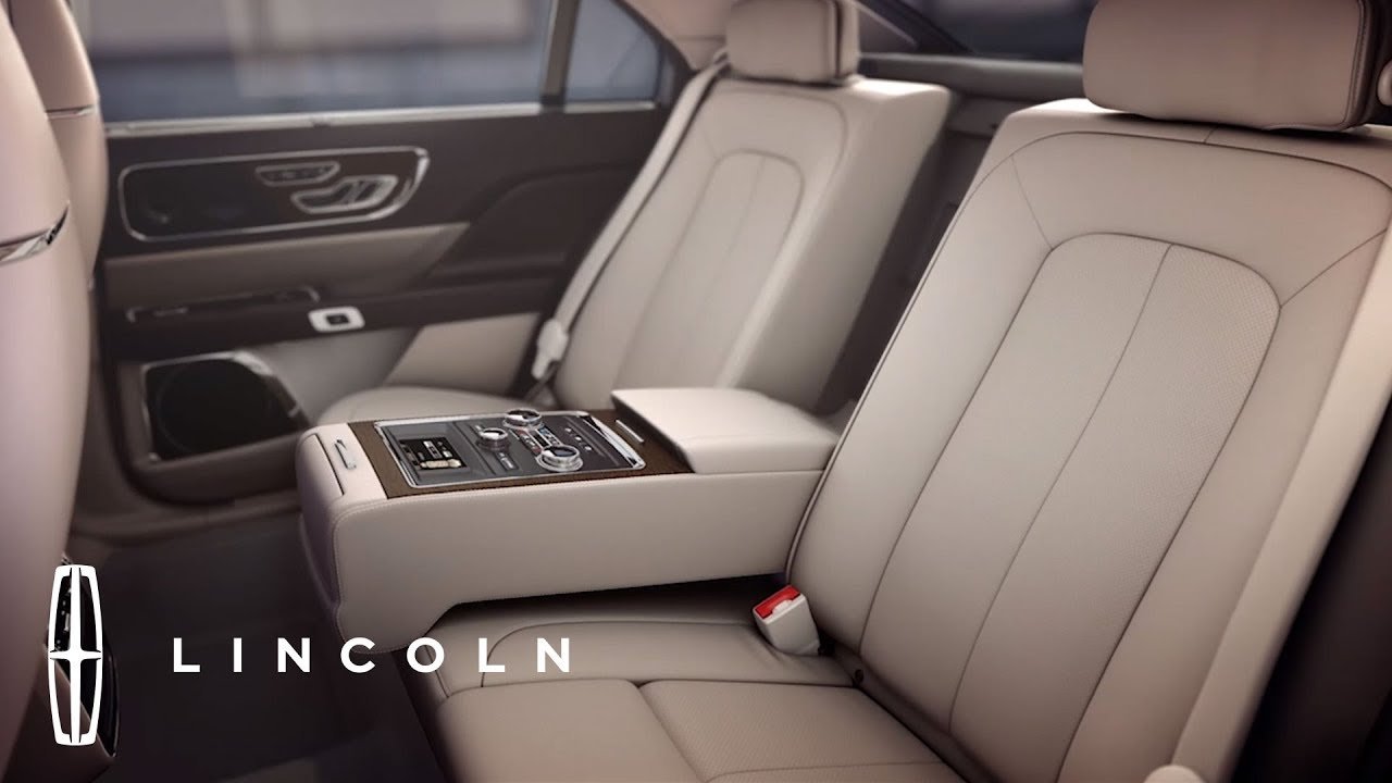 The interior of a luxury car with beige leather seats, a central control console, and the Lincoln logo visible in the bottom left corner.