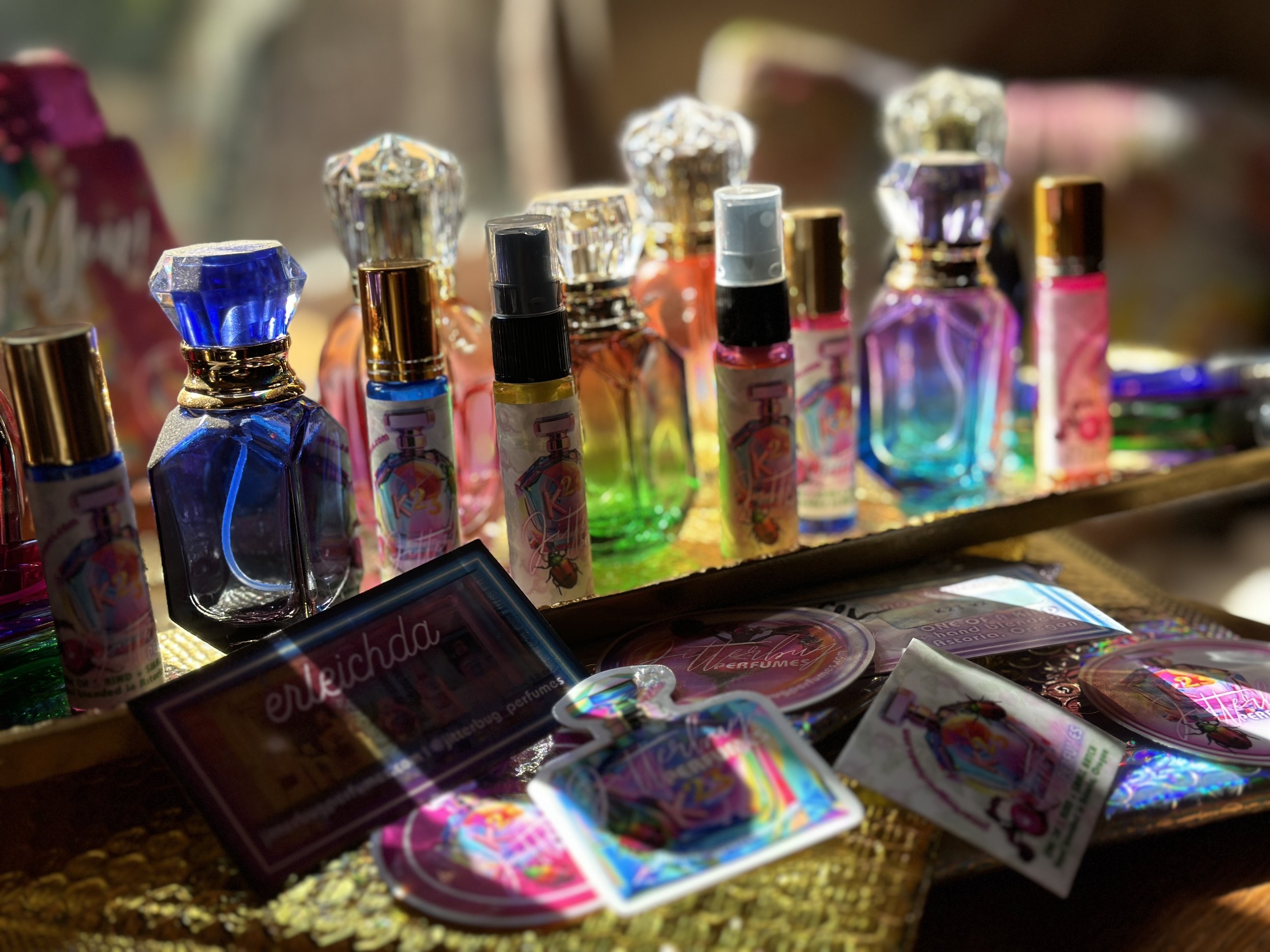 Colorful collection of perfume bottles on display with accessories and packaging in front.