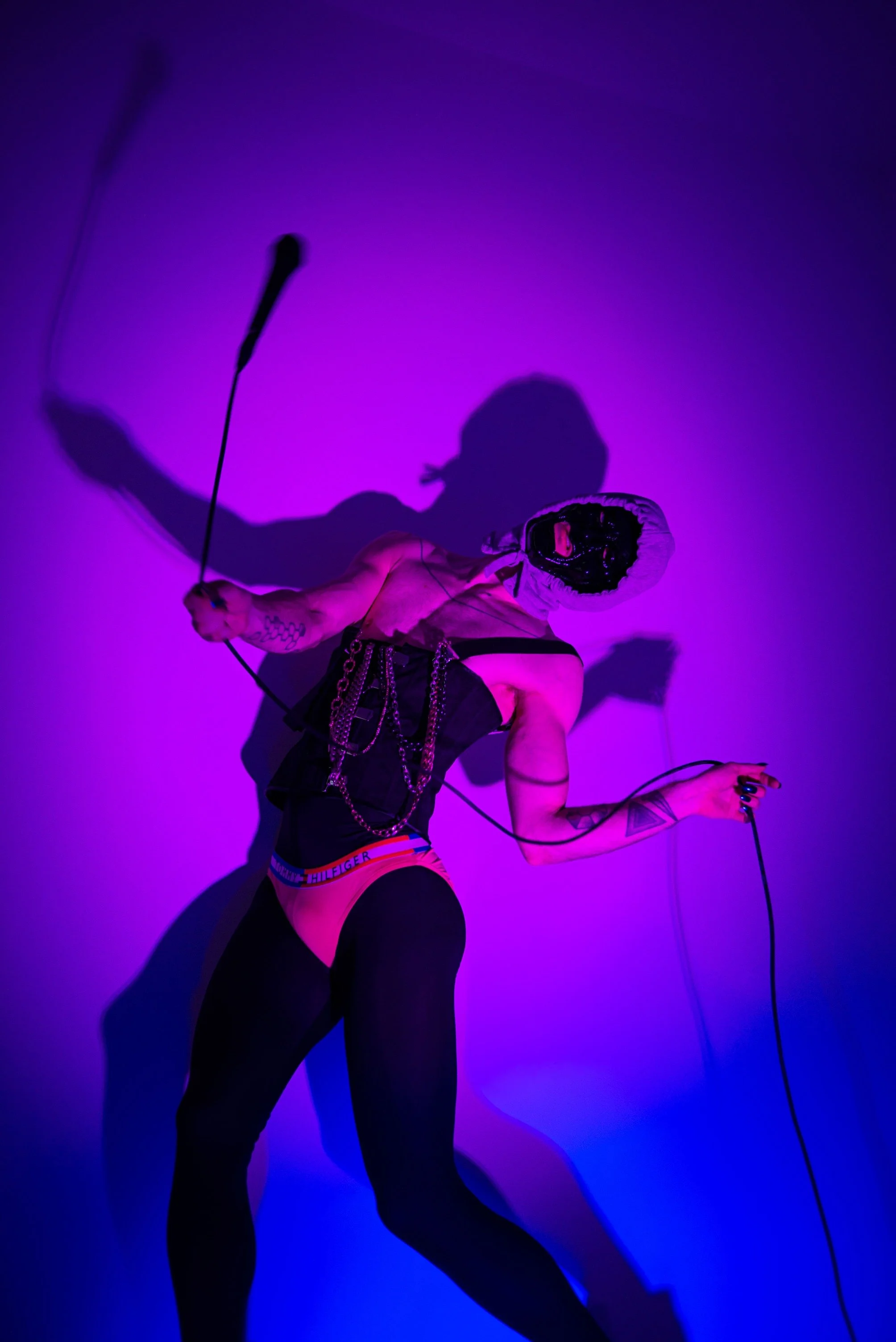 Ave Vanilla - Enfant Terrible: Fine art performance documentation featuring a dynamic, sculptural silhouette against a vibrant purple neon background with a dramatic shadow[cite: 33].